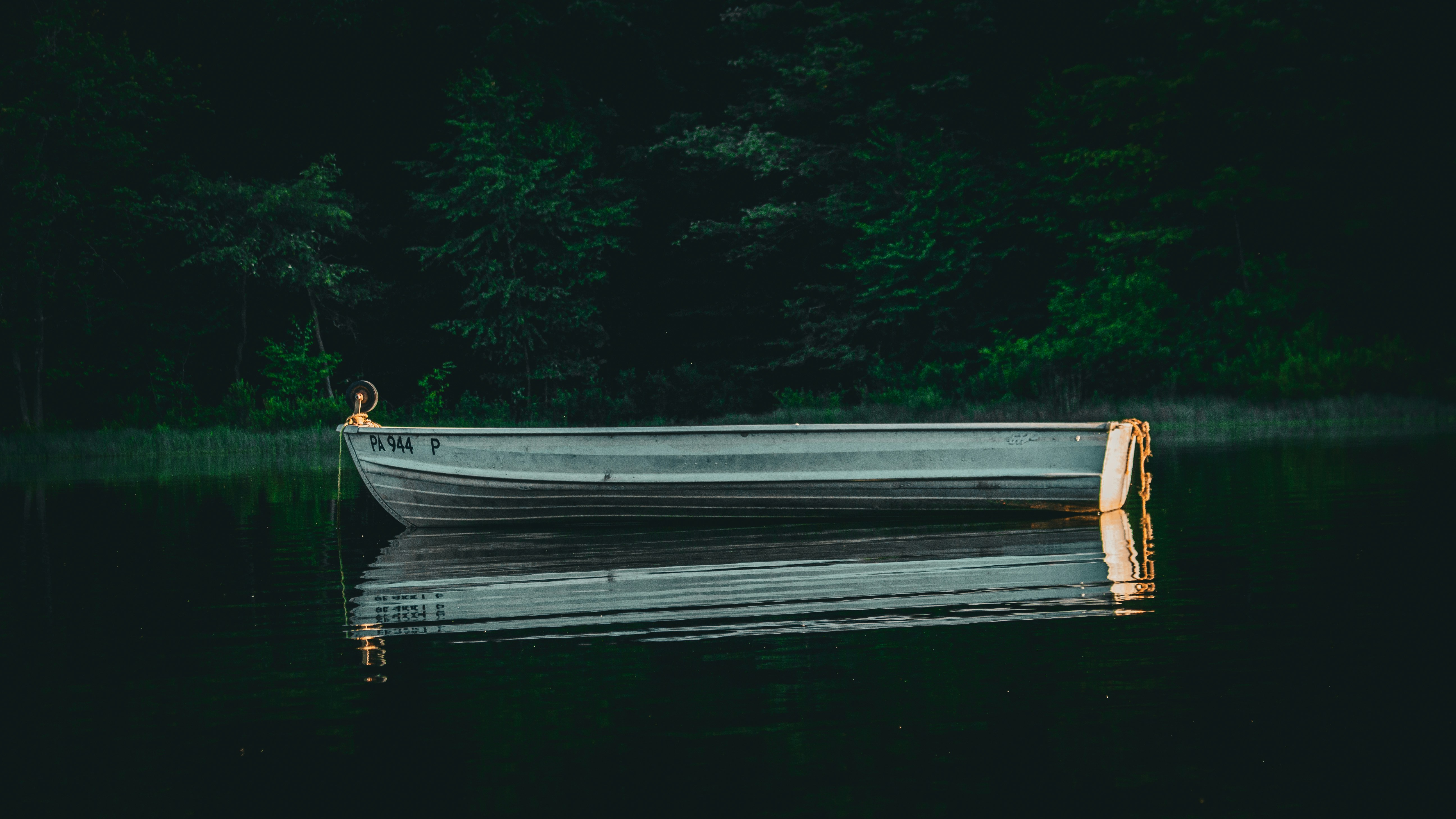 A lone rowboat floats on a dark, still lake.
