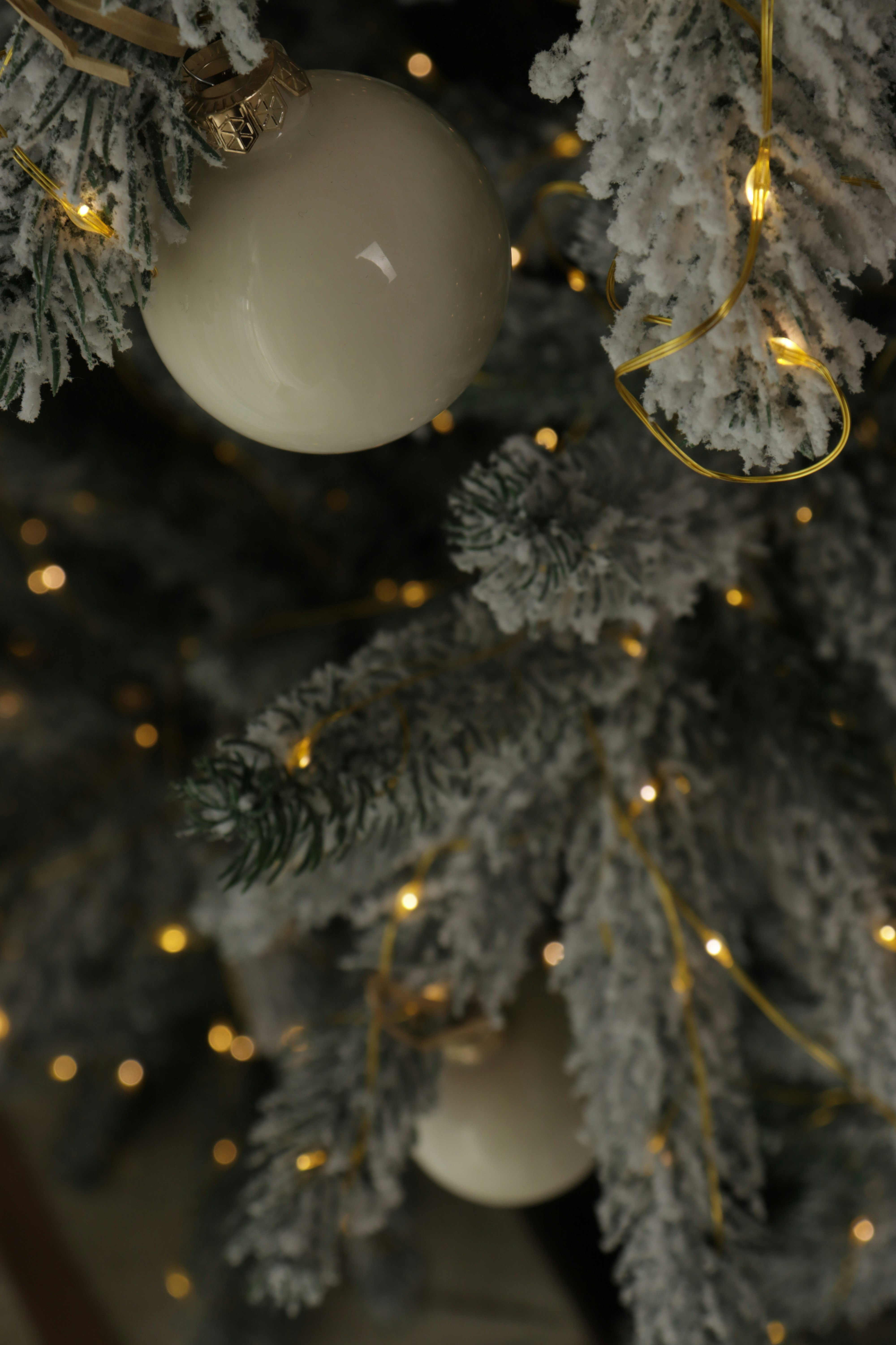 Close up of a frosted christmas tree with ornaments.