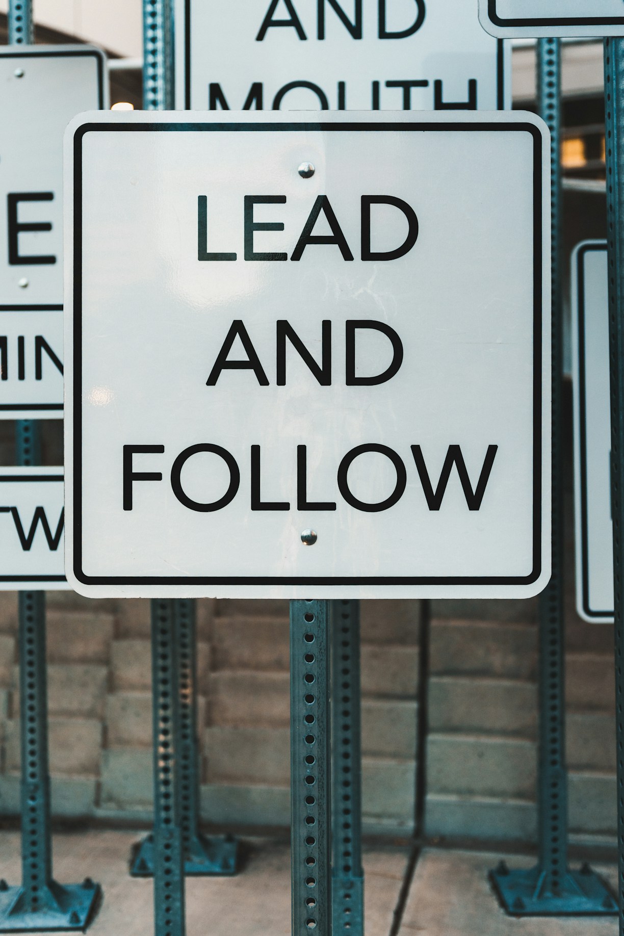 White sign with black text: lead and follow