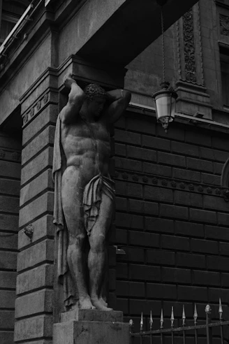 Stone statue of a man holding up an archway.