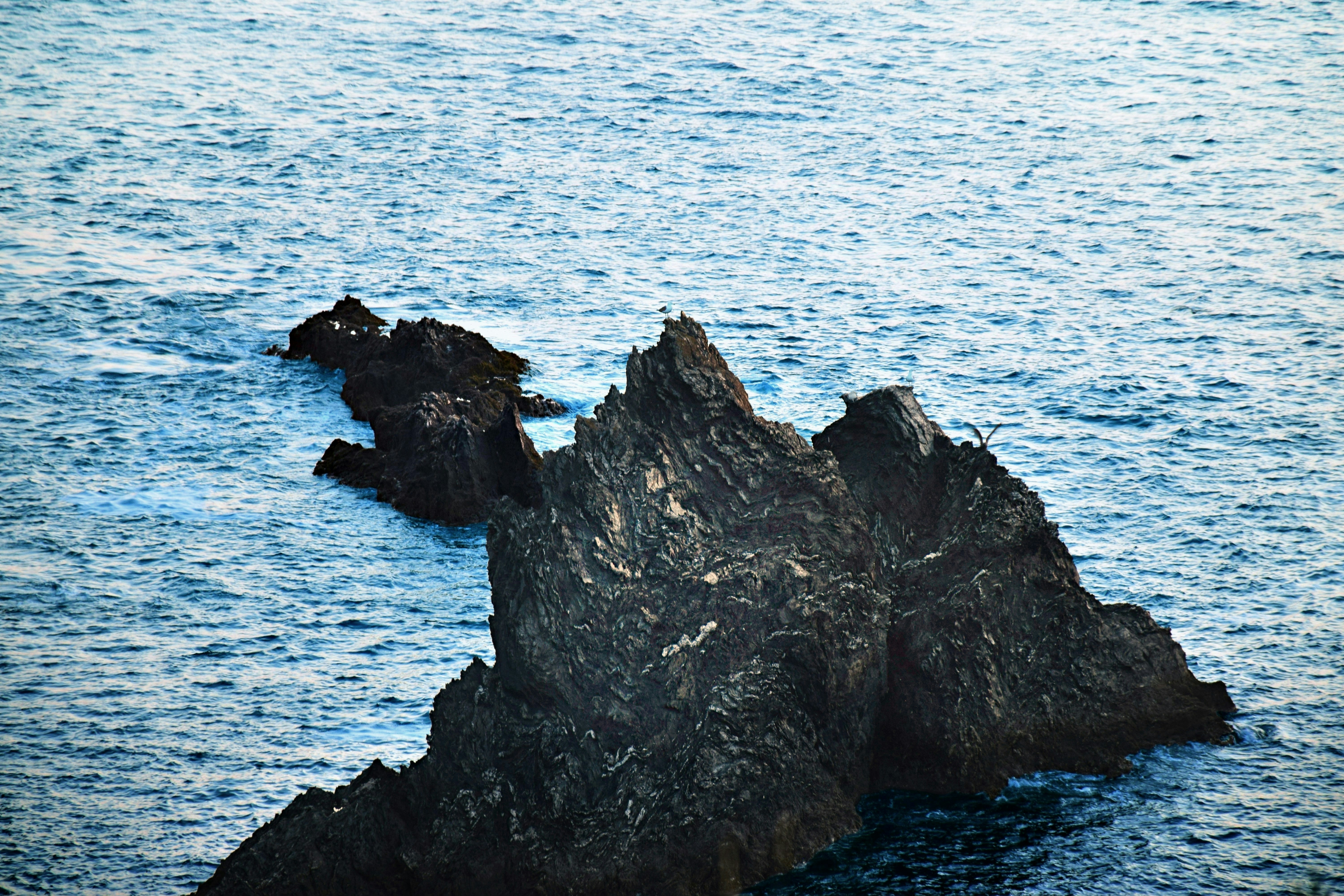 Jagged rock formation emerging from blue ocean waves