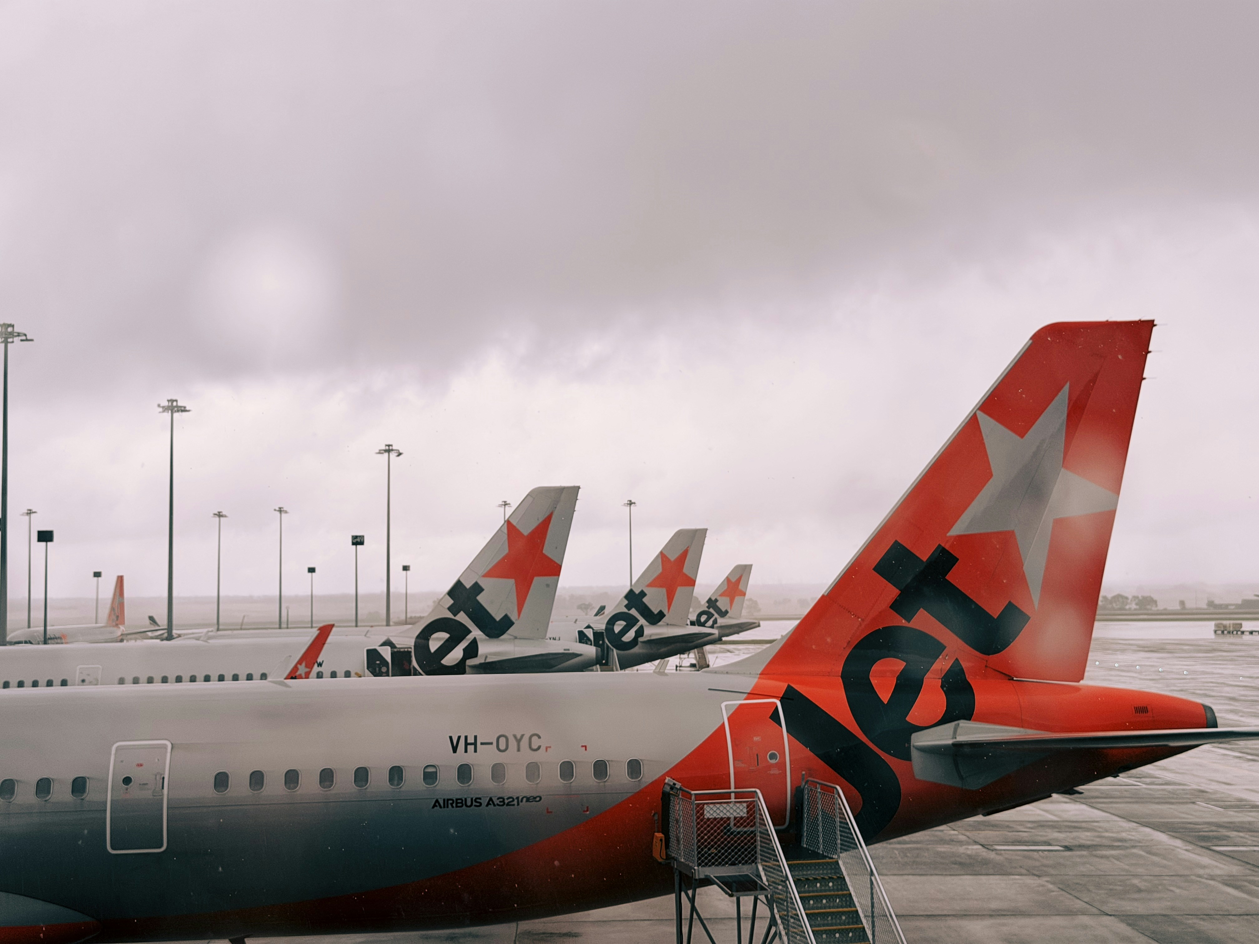 Jetstar airplanes lined up on a cloudy day