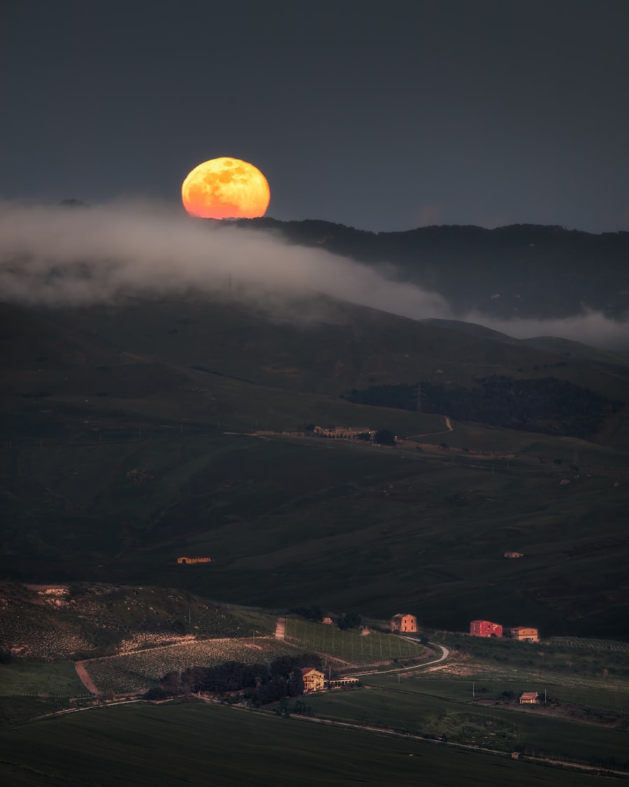 Full moon rising over misty rolling hills at dusk, photo by Marco Grosso on Unsplash