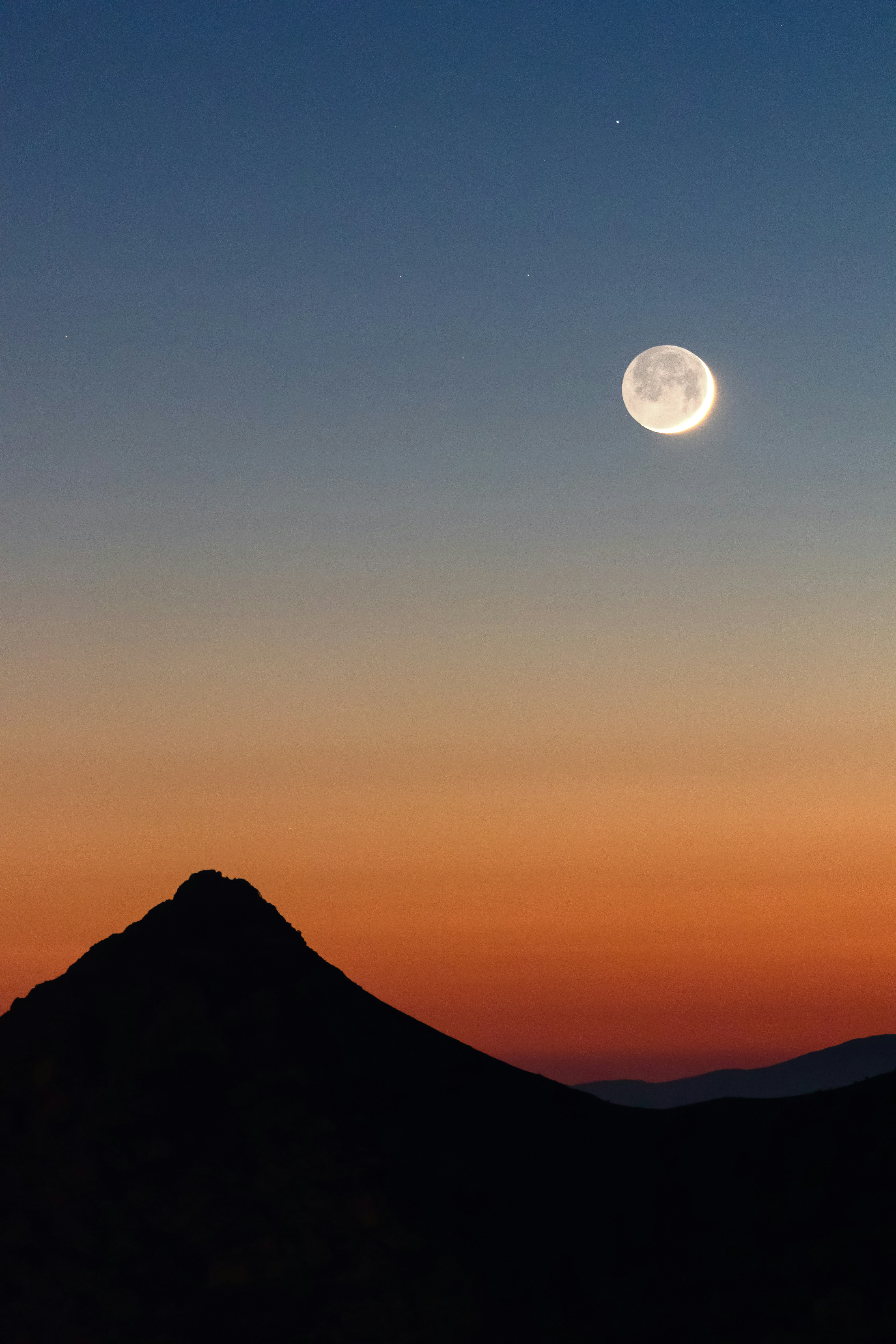 Full moon over mountain silhouette at sunset