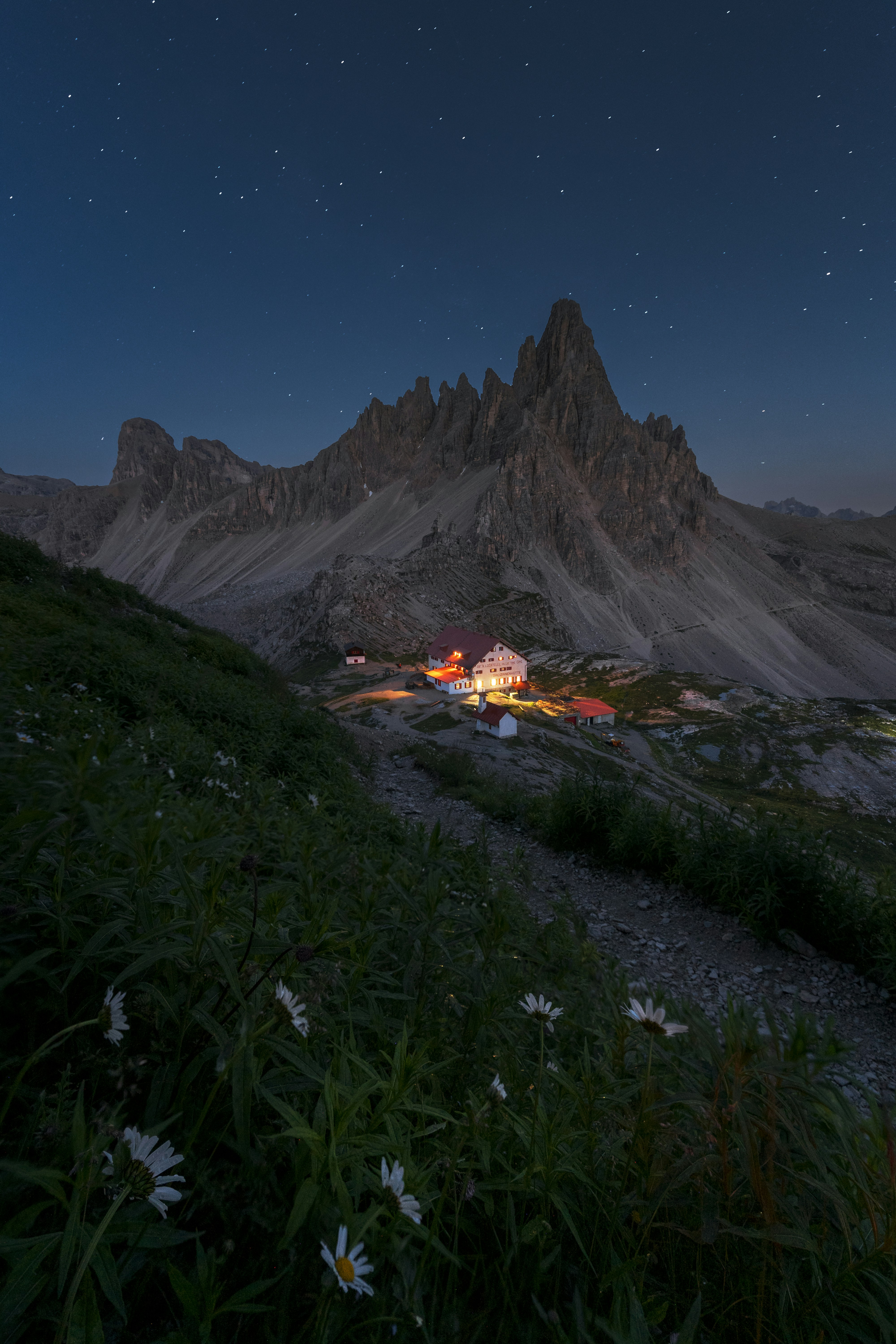 Mountain refuge illuminated at night under starry sky.