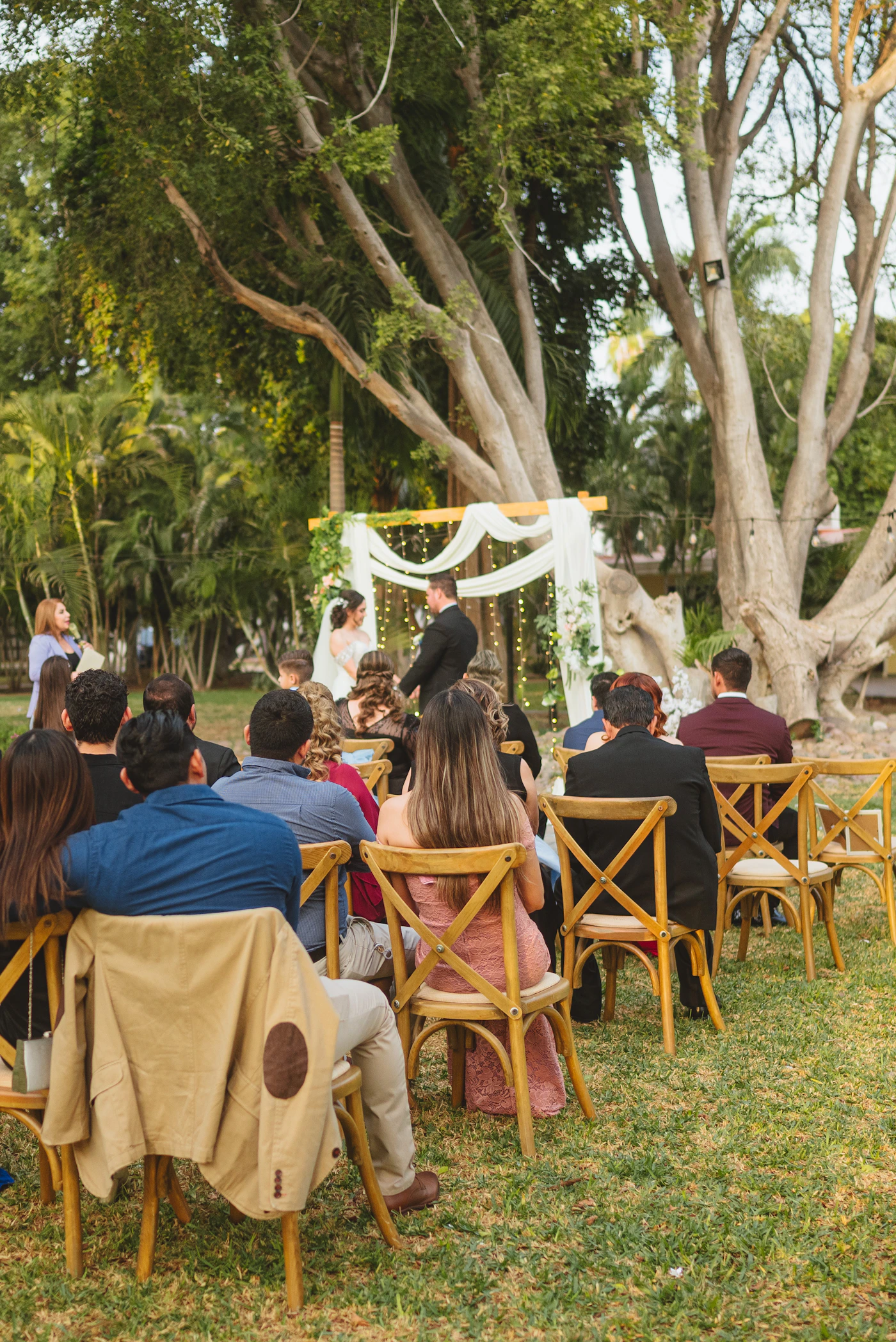 Rows of wedding guests seated outdoors watching the wedding ceremony with the aisle leading to the couple