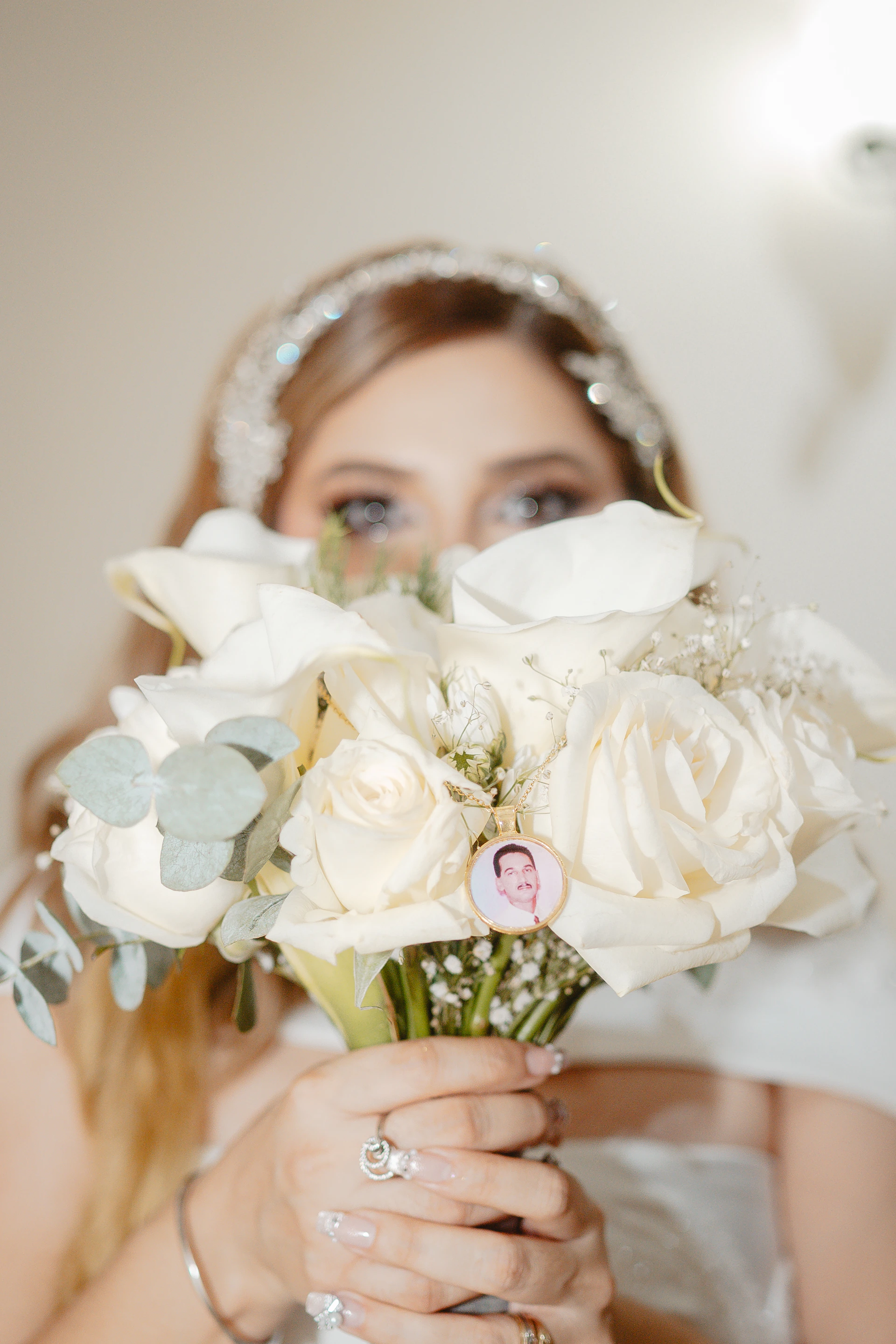 Bride holding white roses with a photo charm
