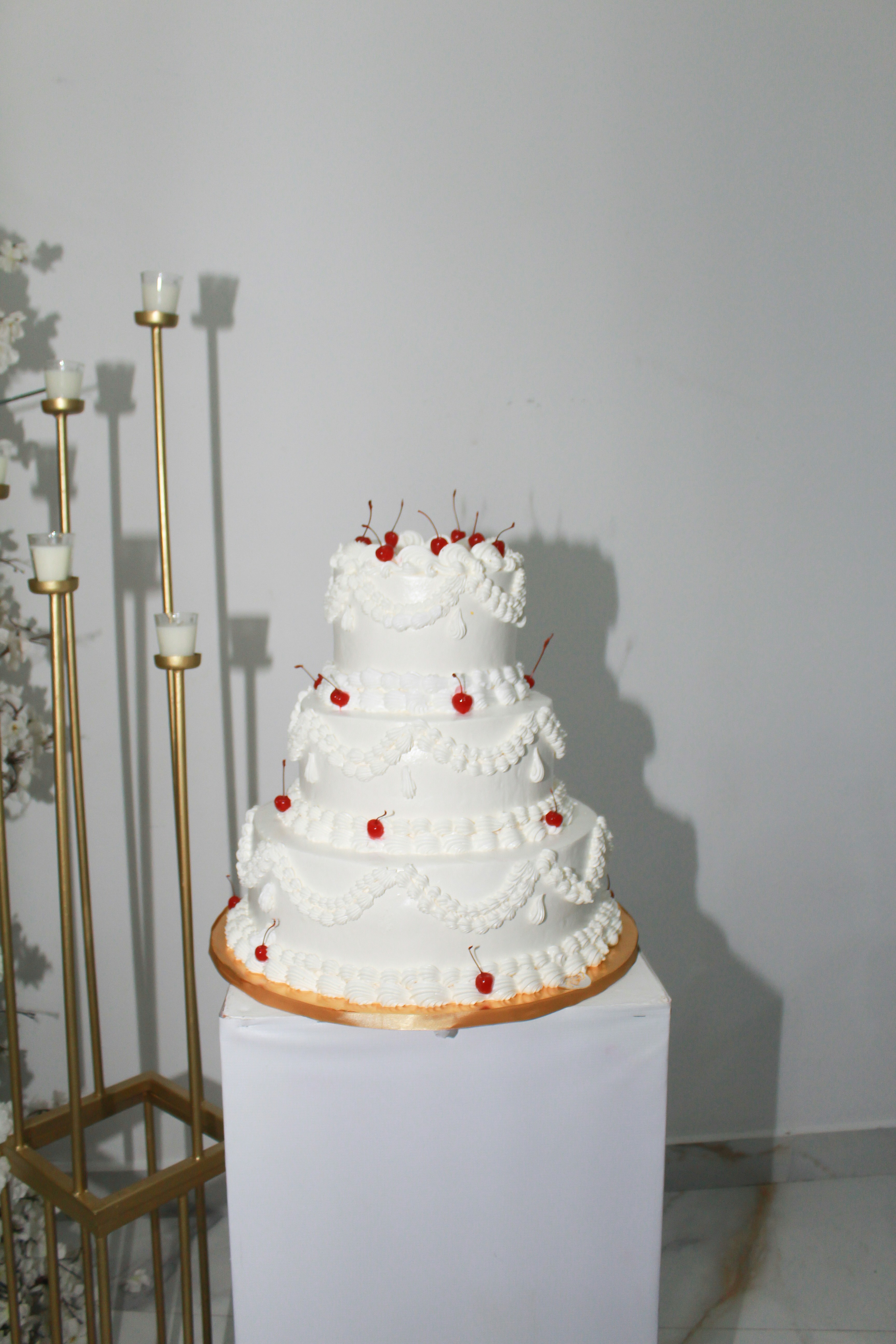 A tiered white cake decorated with cherries.