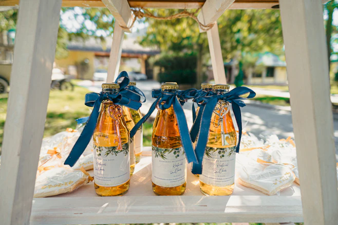 Three glass bottles with golden liquid and blue ribbons