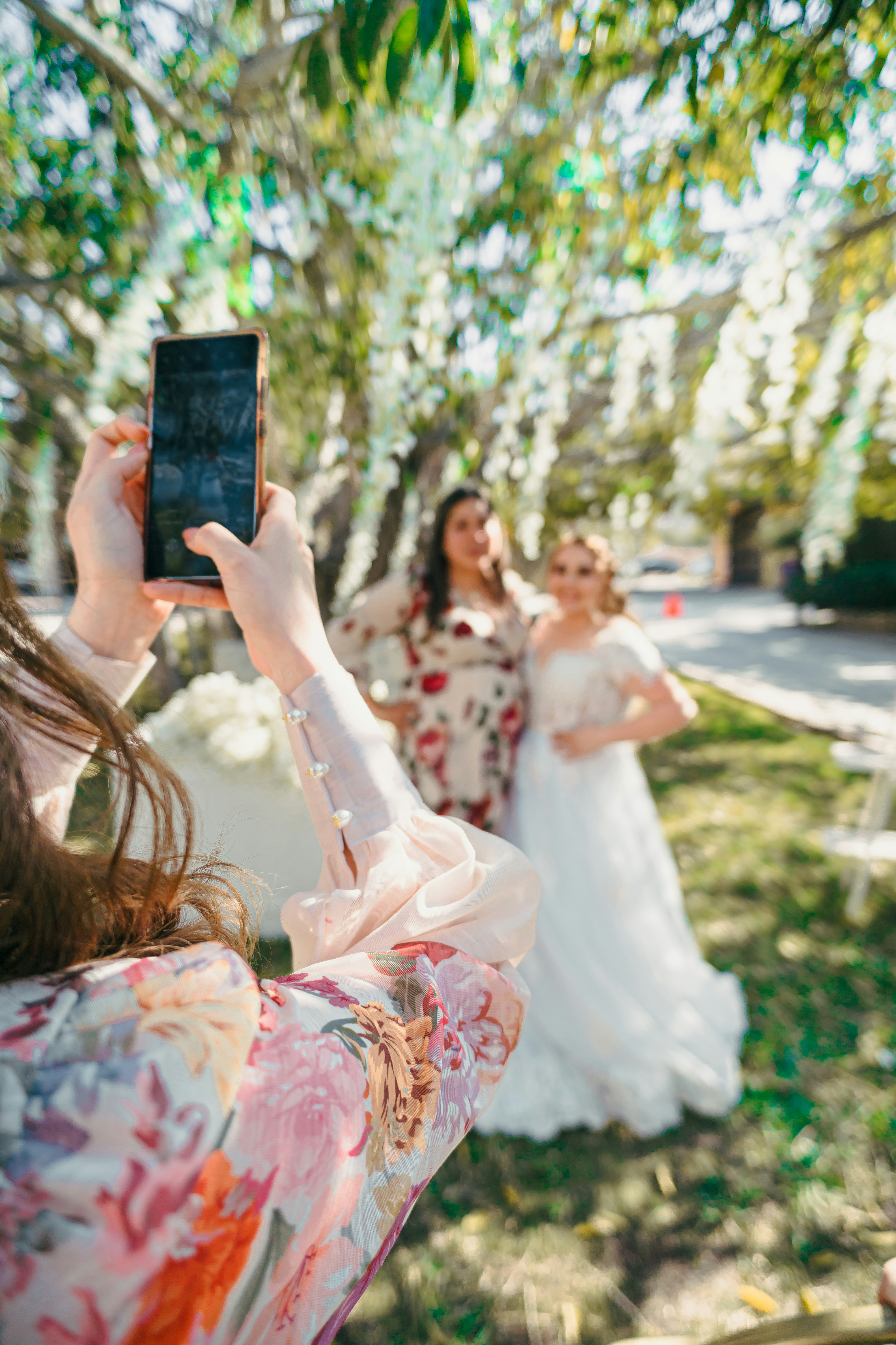 Woman in floral dress photographs bride outdoors