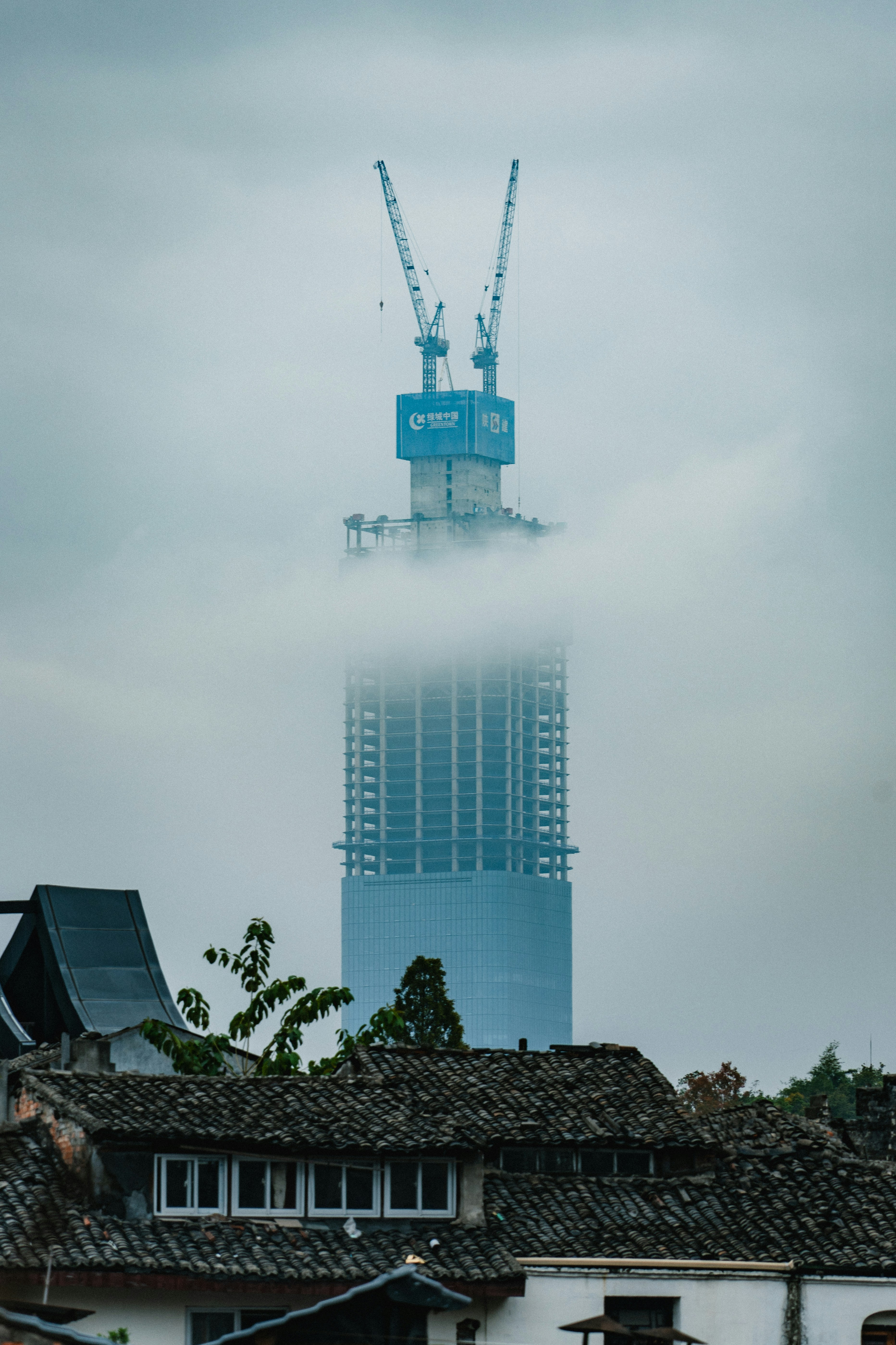 Skyscraper under construction shrouded in fog.