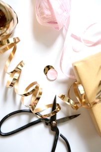 Gold ribbon, scissors, and gift wrapping supplies.