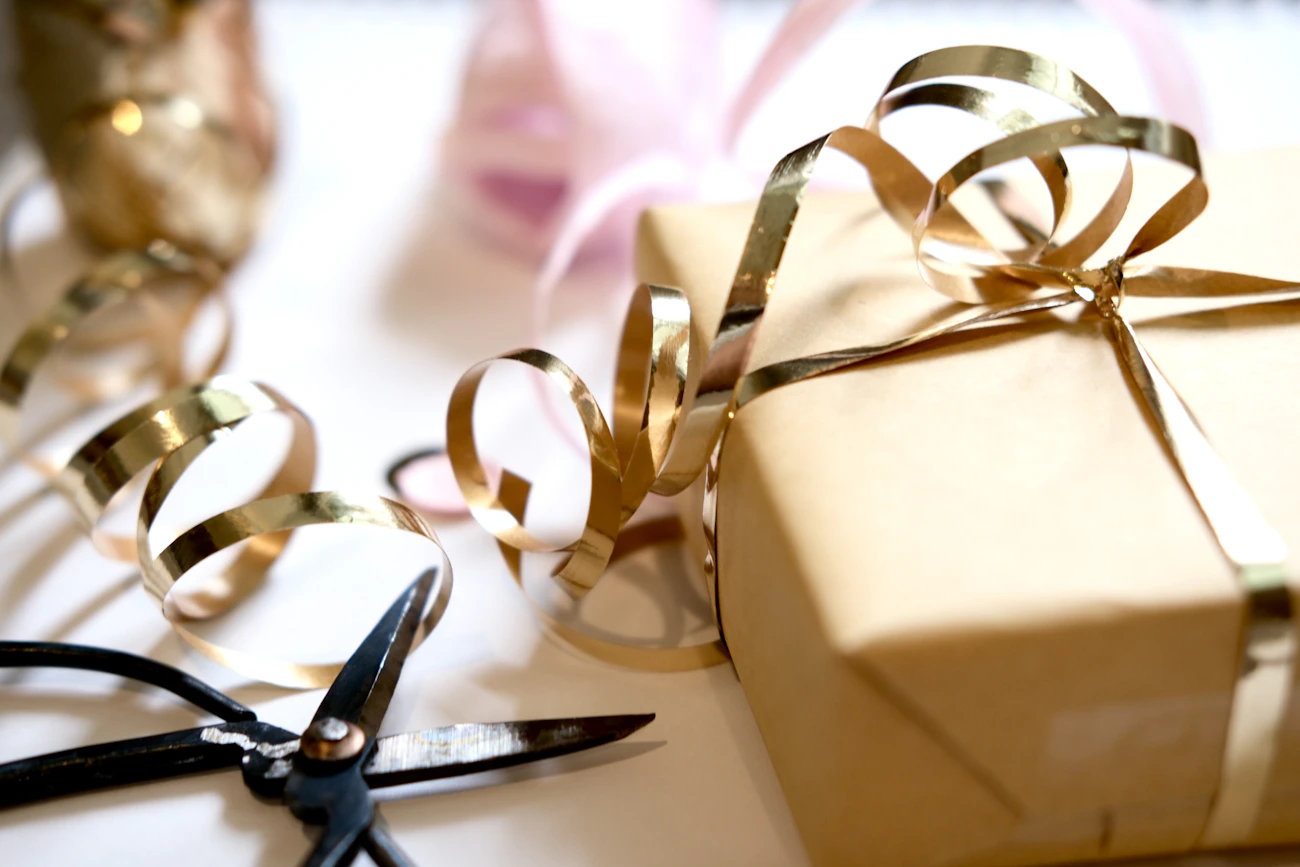 Gift wrapping station with scissors, ribbon, paper, and celebration details