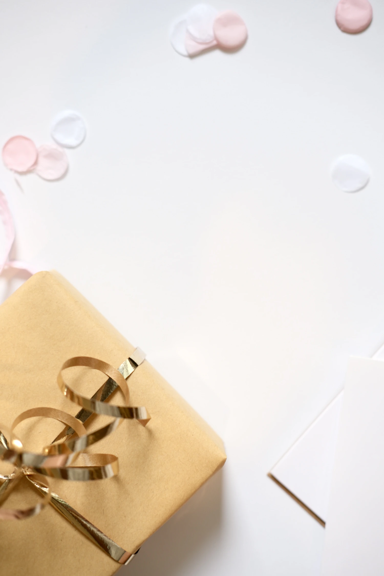 Wrapped gift with gold ribbon, greeting card, and festive confetti