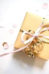 A golden gift box tied with pink and gold ribbons.