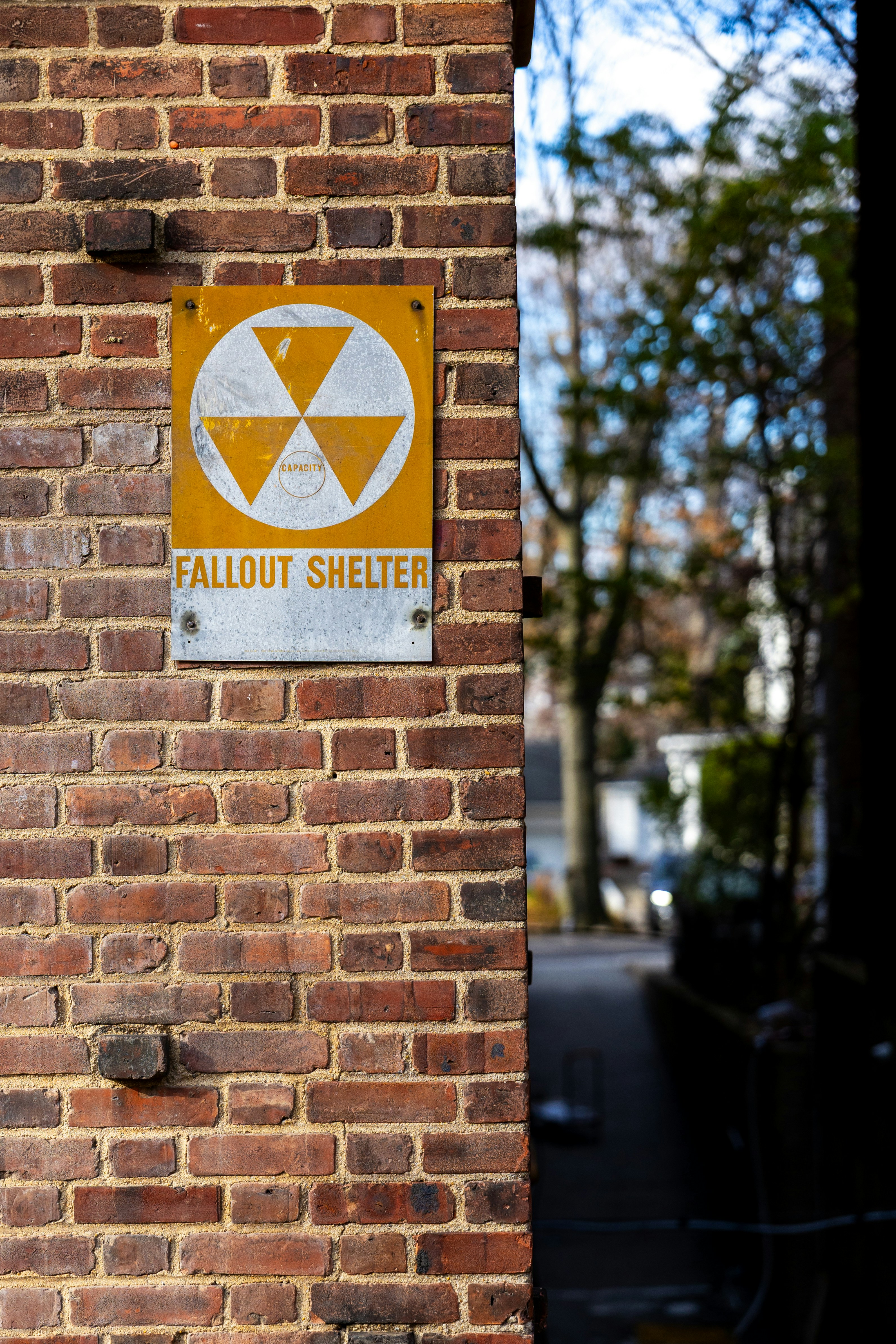 Fallout shelter sign on a brick wall.