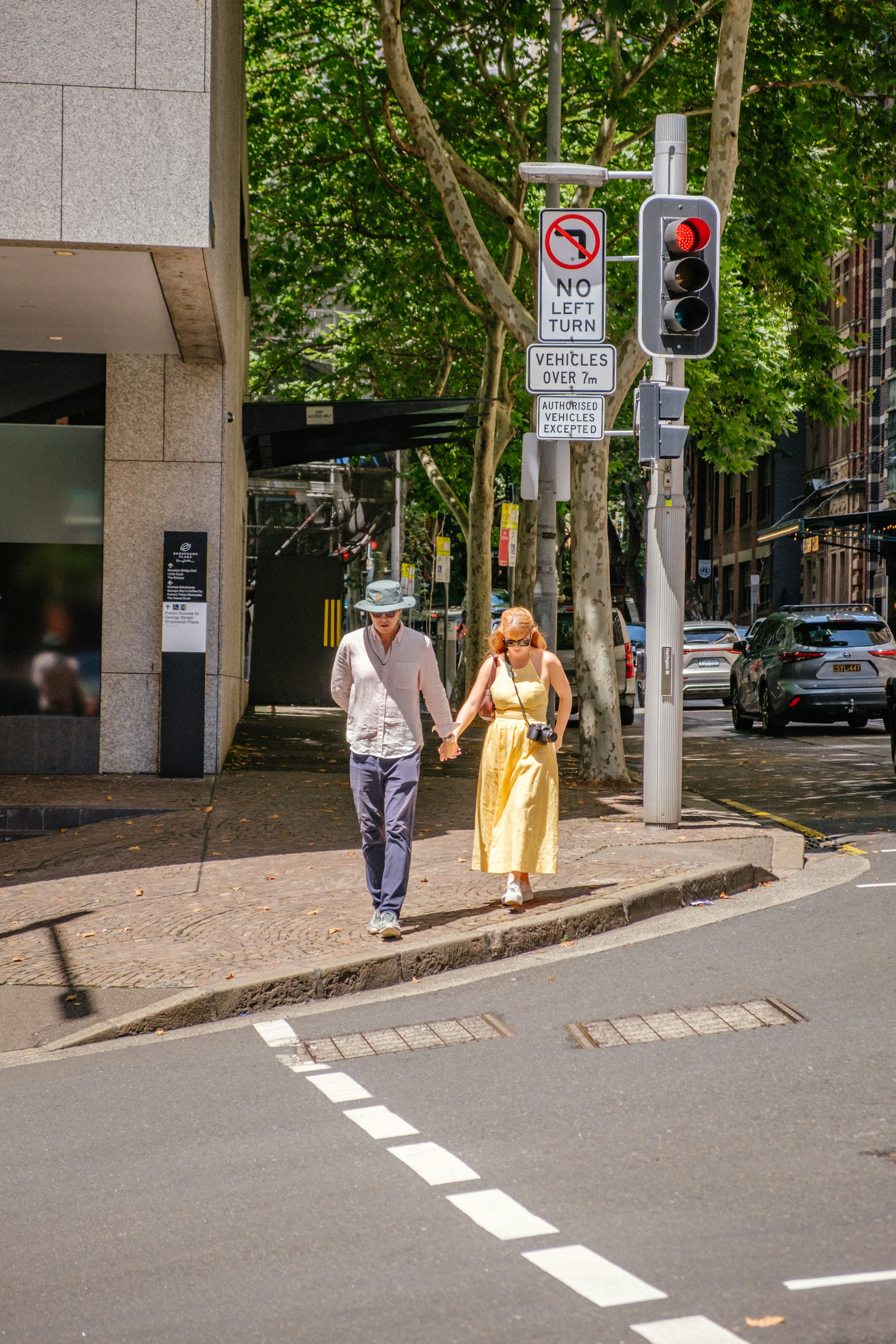 Pareja cogida de la mano caminando por la acera de la ciudad