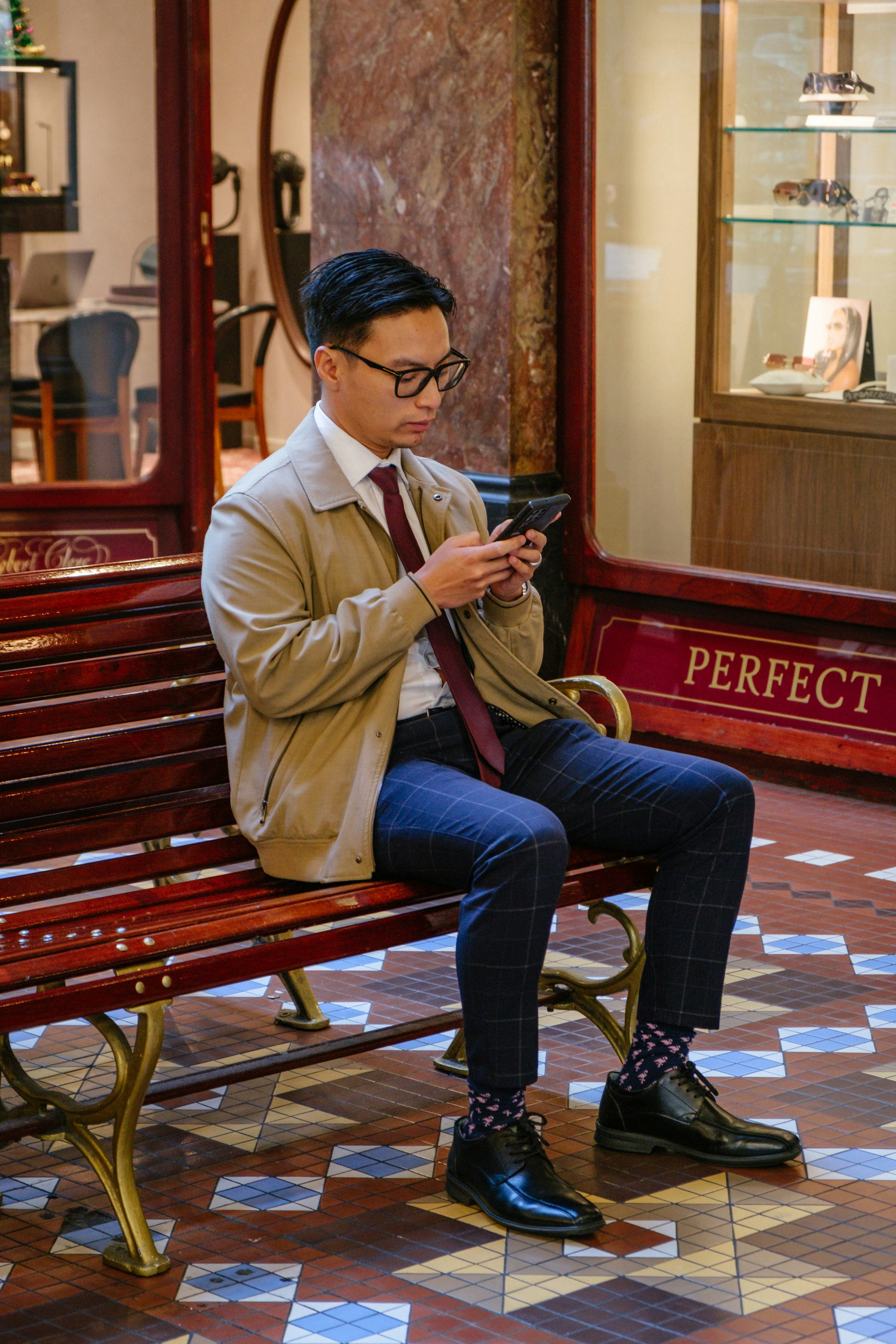 Hombre con traje sentado en un banco usando un smartphone