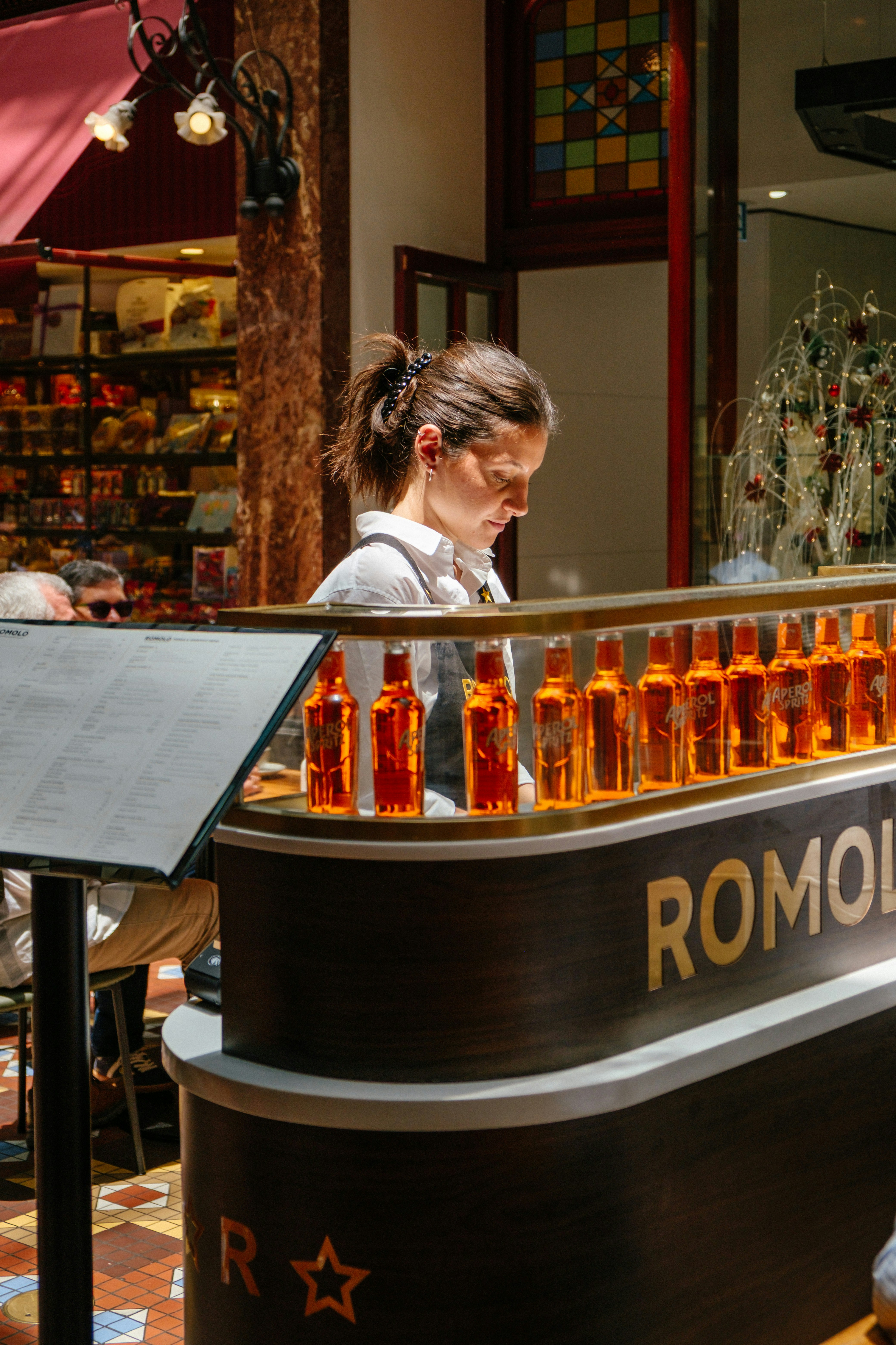 Woman behind a bar with bottles of orange liqueur