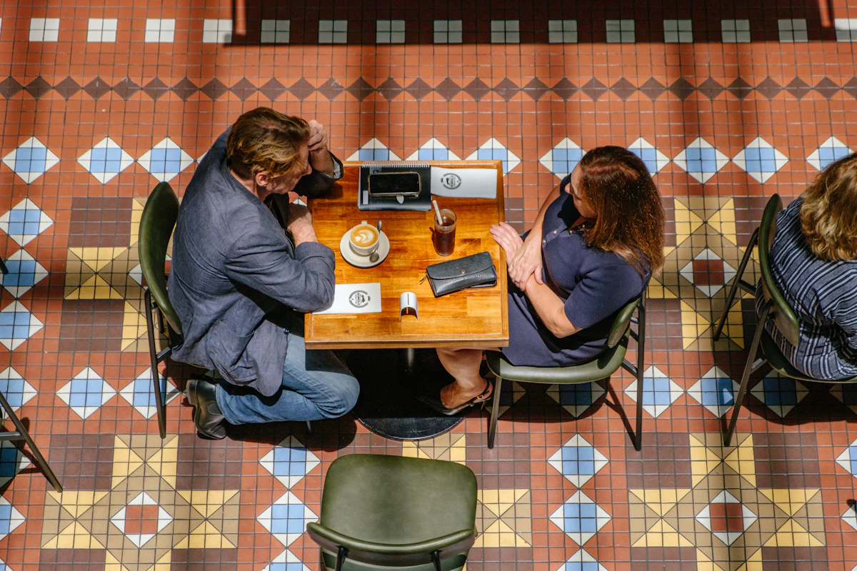 Two people sitting across from each other at a cafe table with coffee on a first blind date