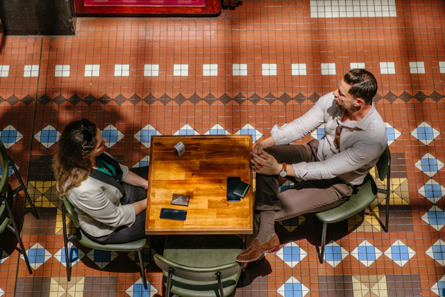 Couple playing cards at a wooden table.