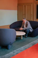 Man in suit sitting on sofa using phone