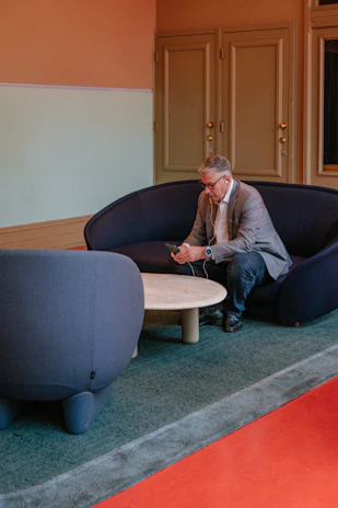 Man in suit sitting on sofa using phone