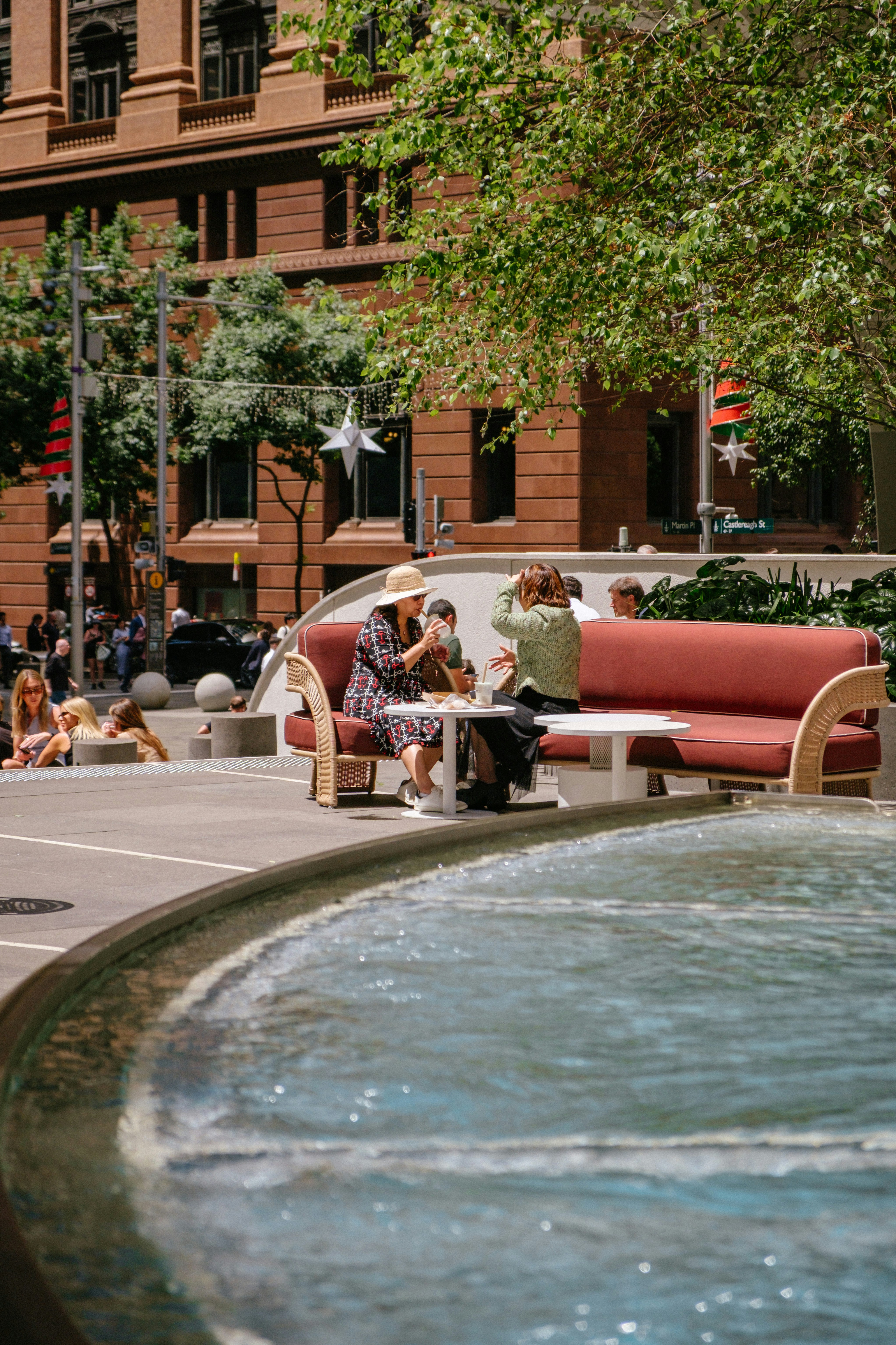 Gente relajándose junto a una fuente en una plaza de la ciudad.