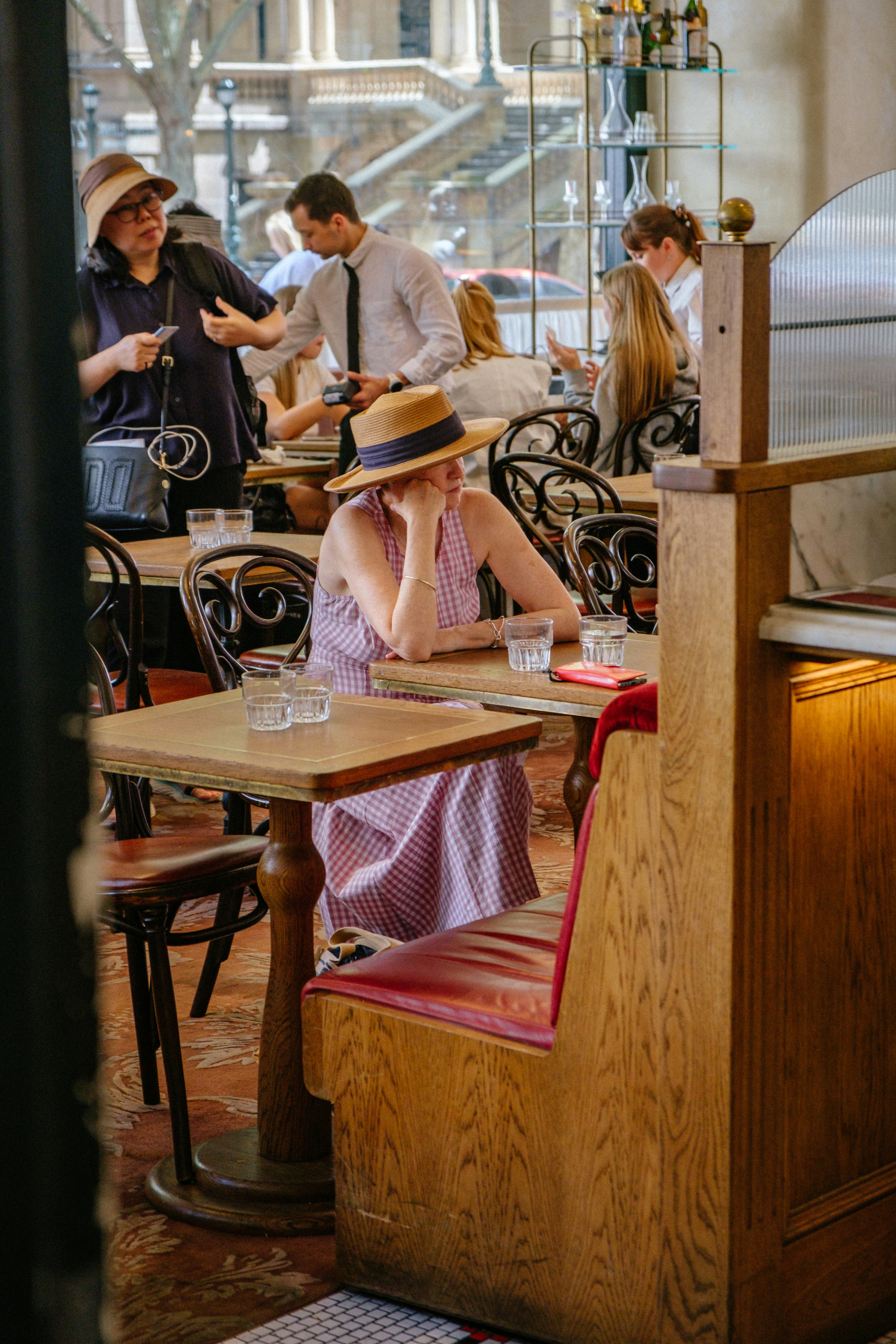 Mujer con sombrero sentada en la mesa del café con bebidas.