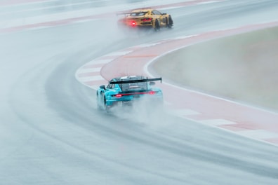Race cars speed through wet track during competition.