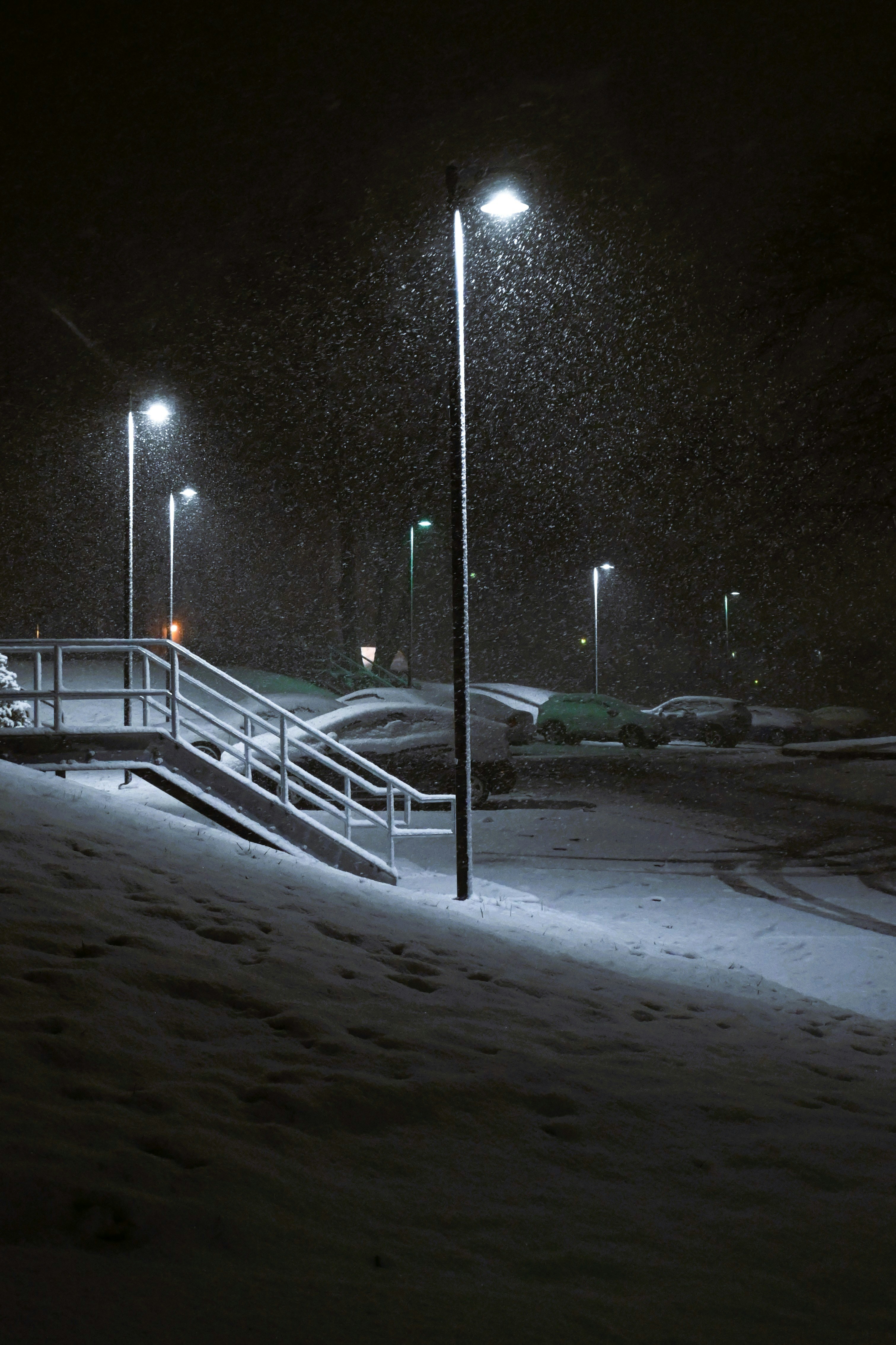 Streetlights illuminate a snowy parking lot at night.