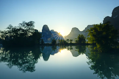 Sunrise over calm water with karst mountains.