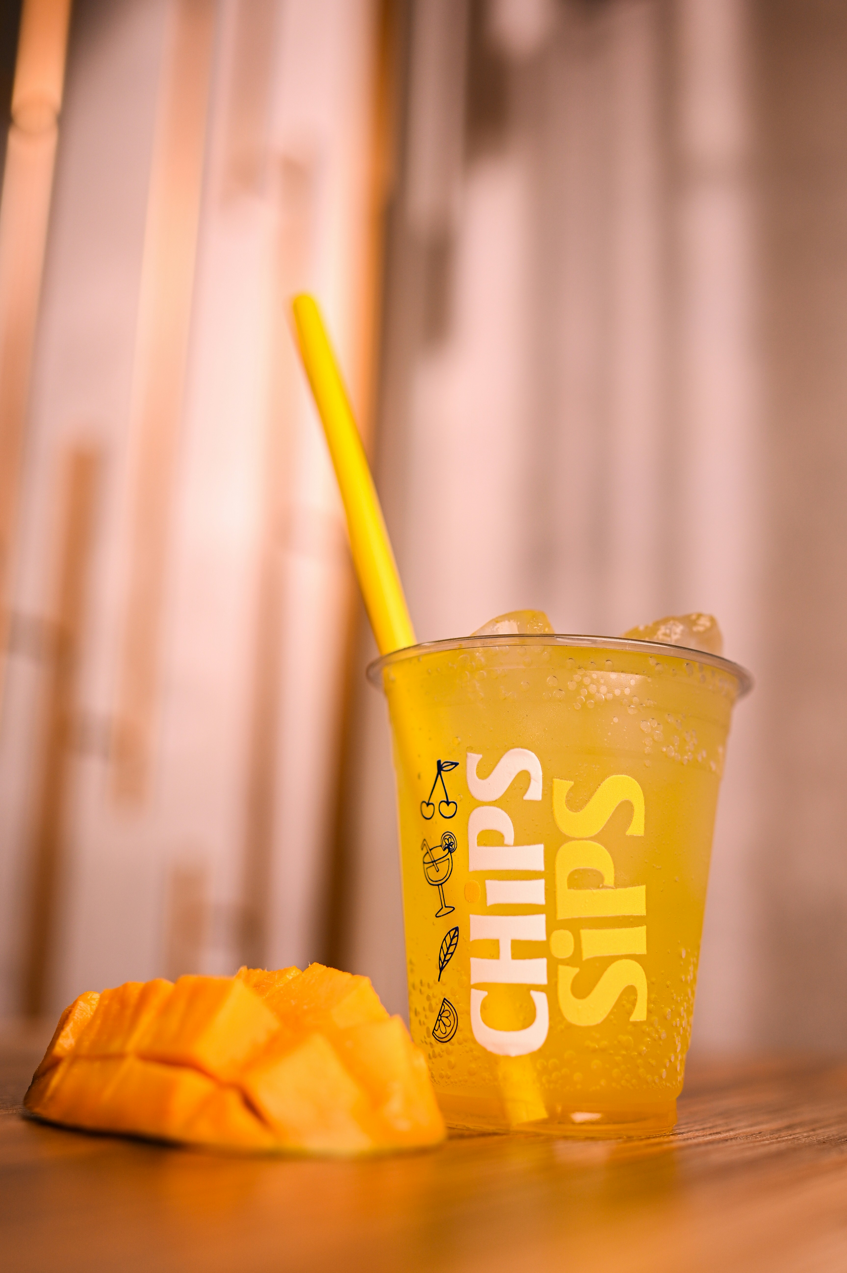 A yellow drink with mango and a straw.