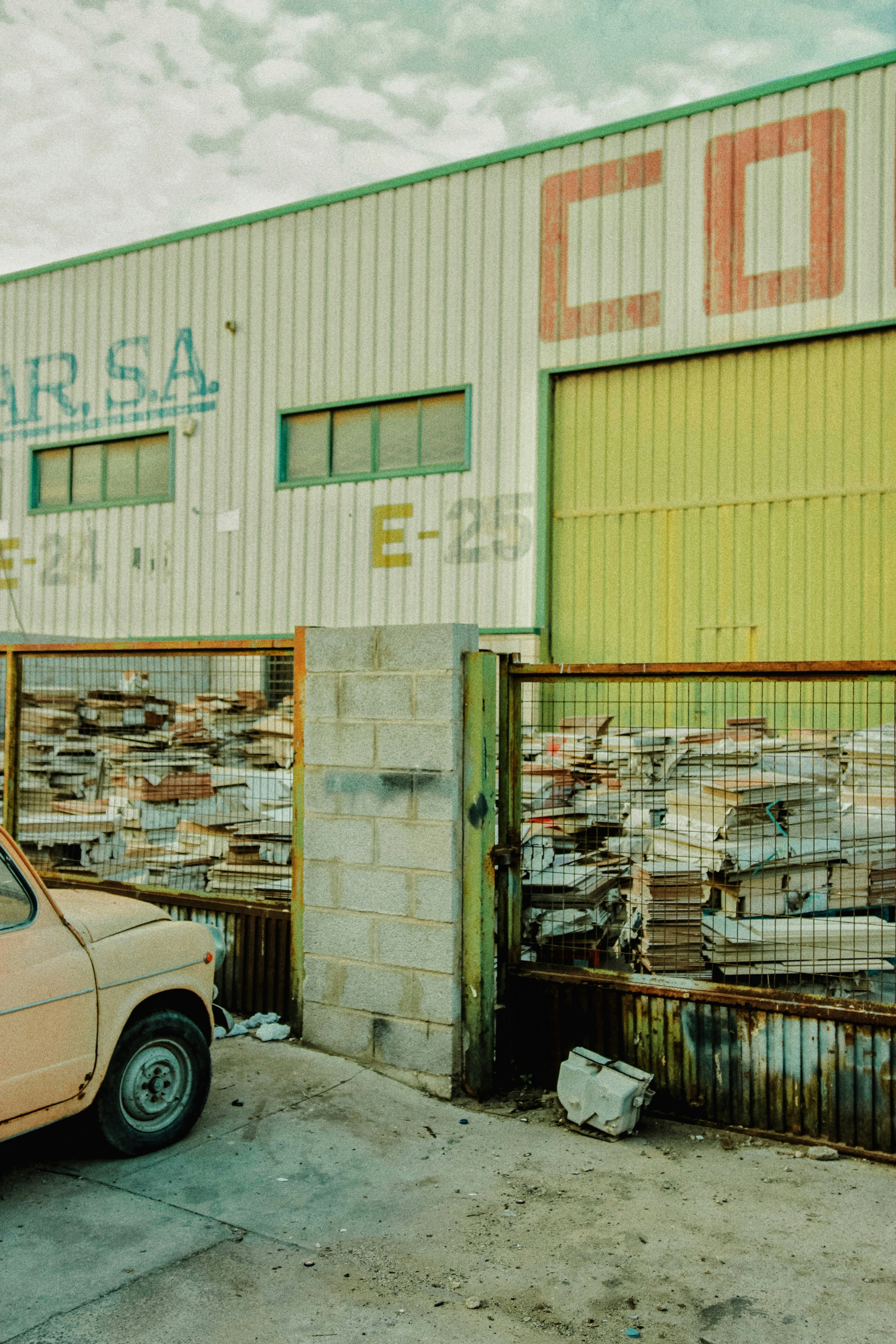 Lagerhaus außen mit gestapelten Materialien und geparktem Auto