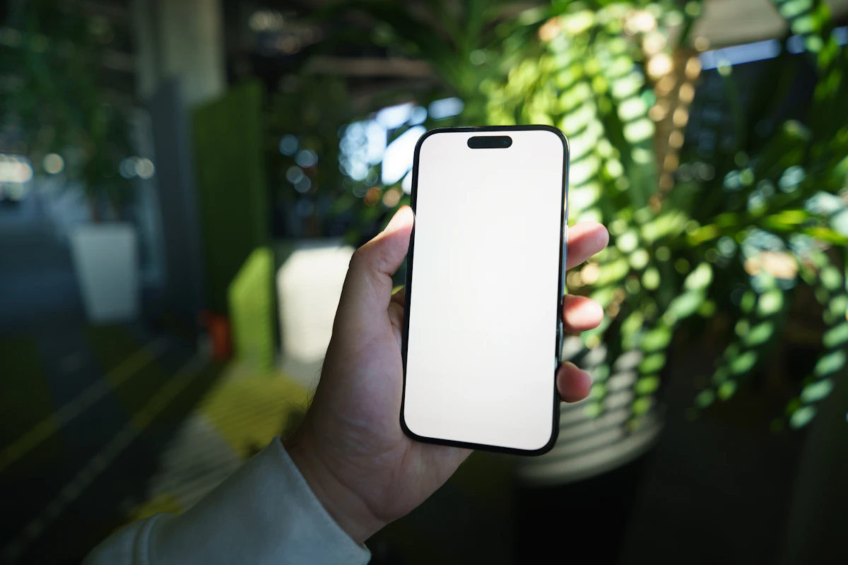 A smartphone held in hand with a bright blank screen