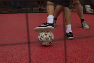 Person balancing soccer ball on red court