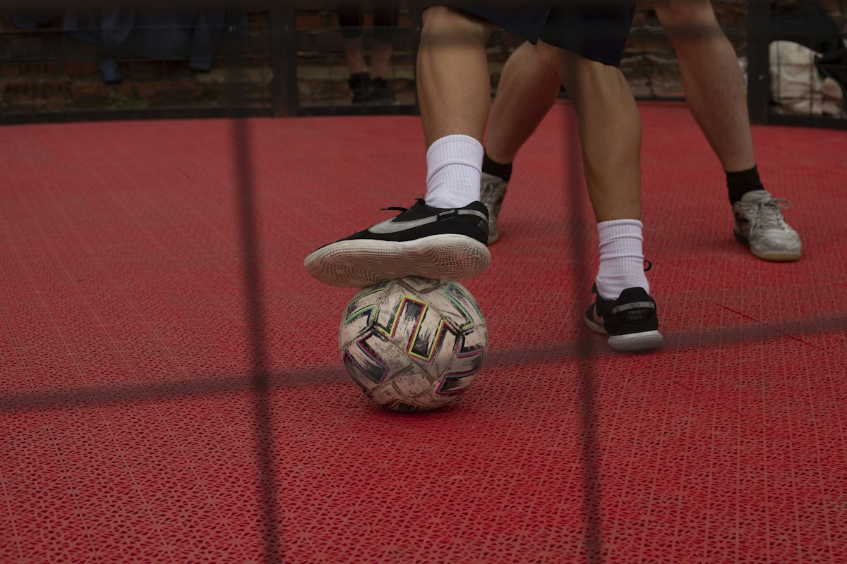 Teen balancing a soccer ball on a red court during a high school gym class activity.