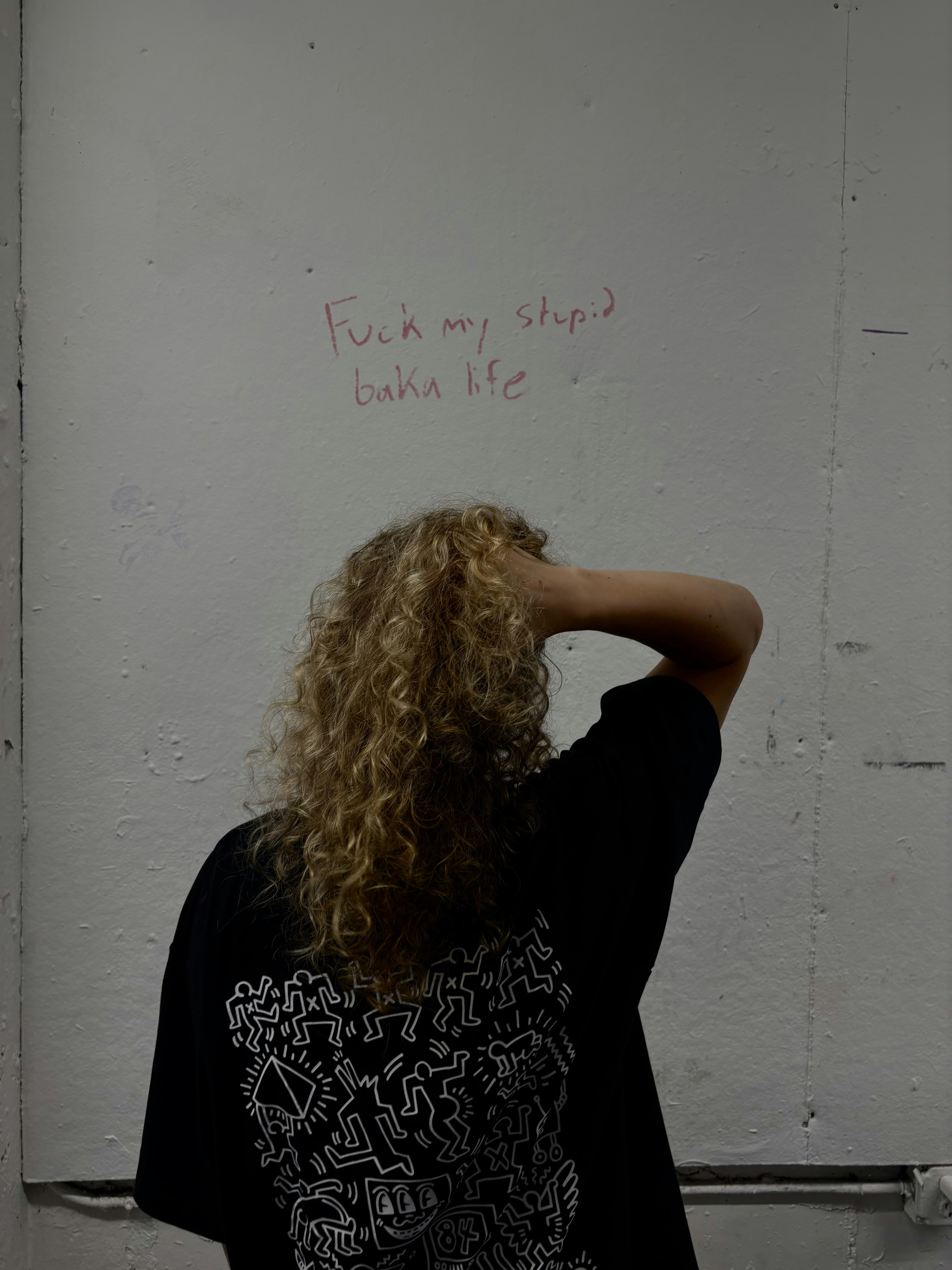 Person with curly hair looking at writing on wall