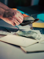 Hands counting money from a wallet over papers.