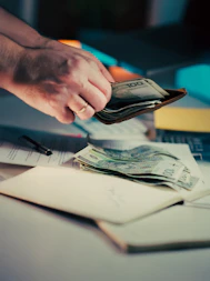 Hands counting money from a wallet over papers