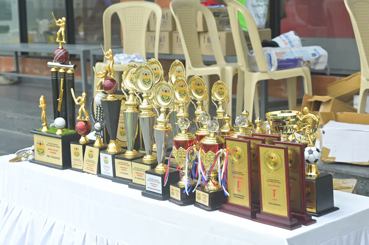 A row of trophies and awards on a draped table.