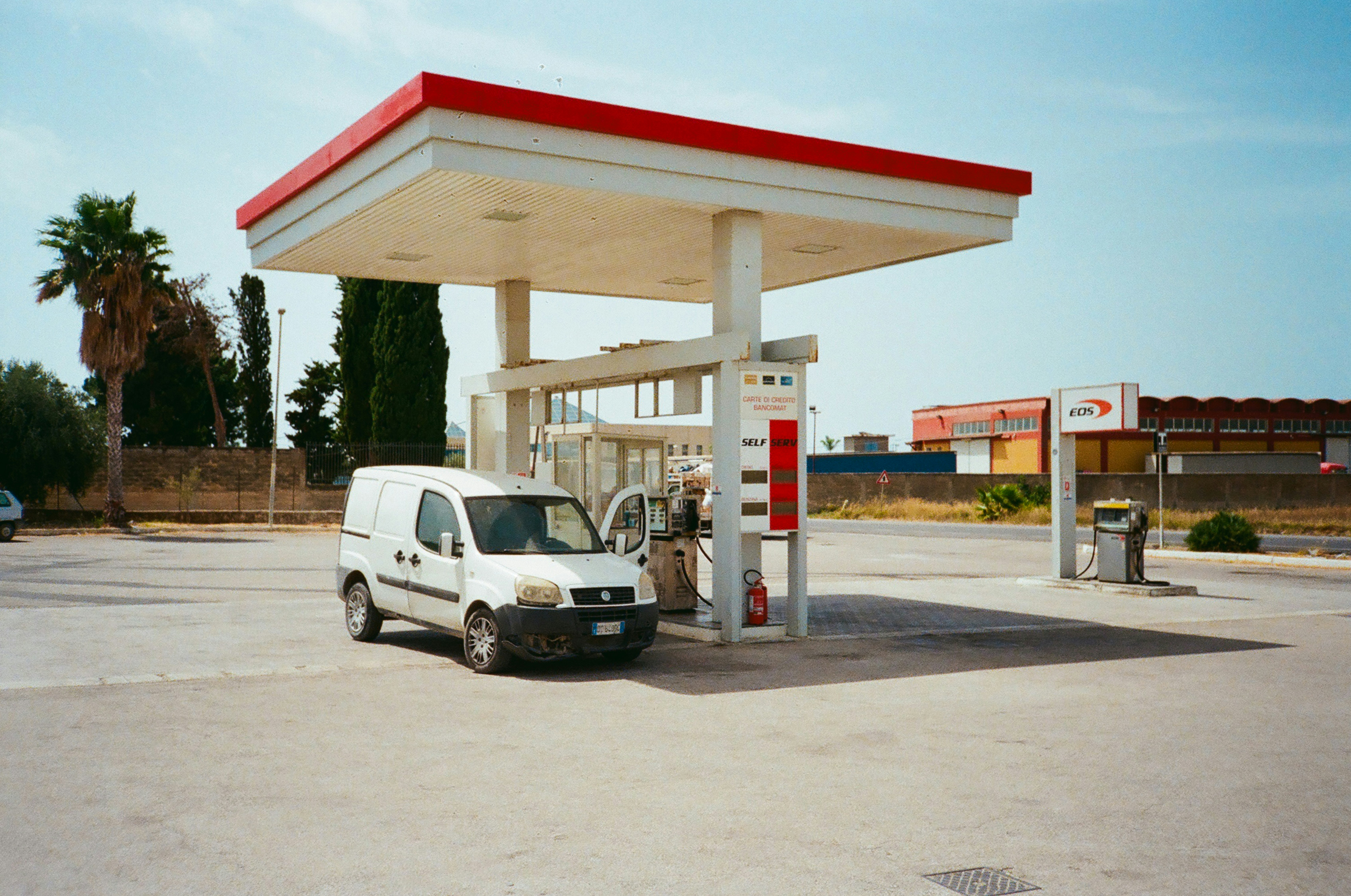 White van at a gas station canopy