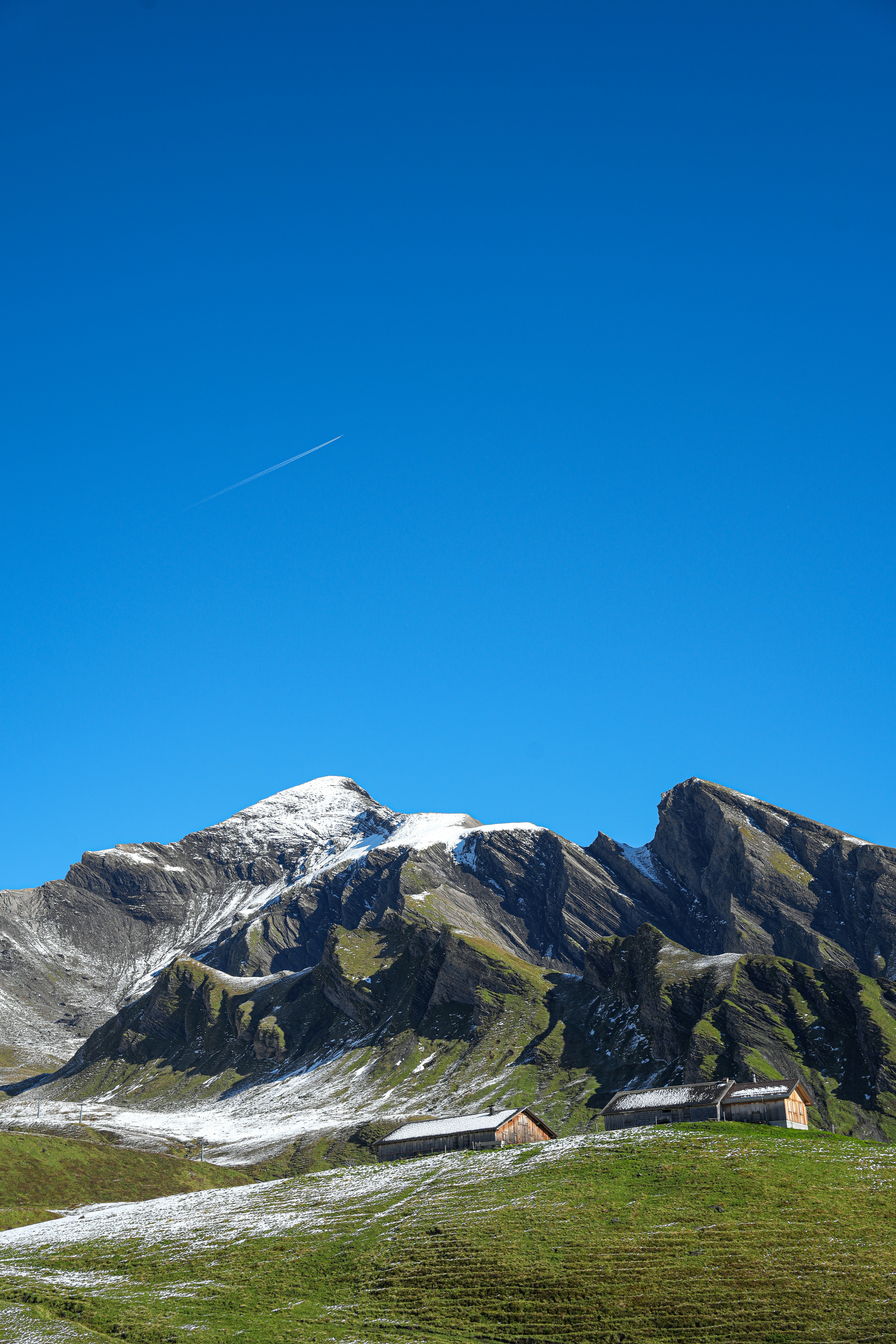 Snow-dusted mountains with cabins under a clear blue sky.