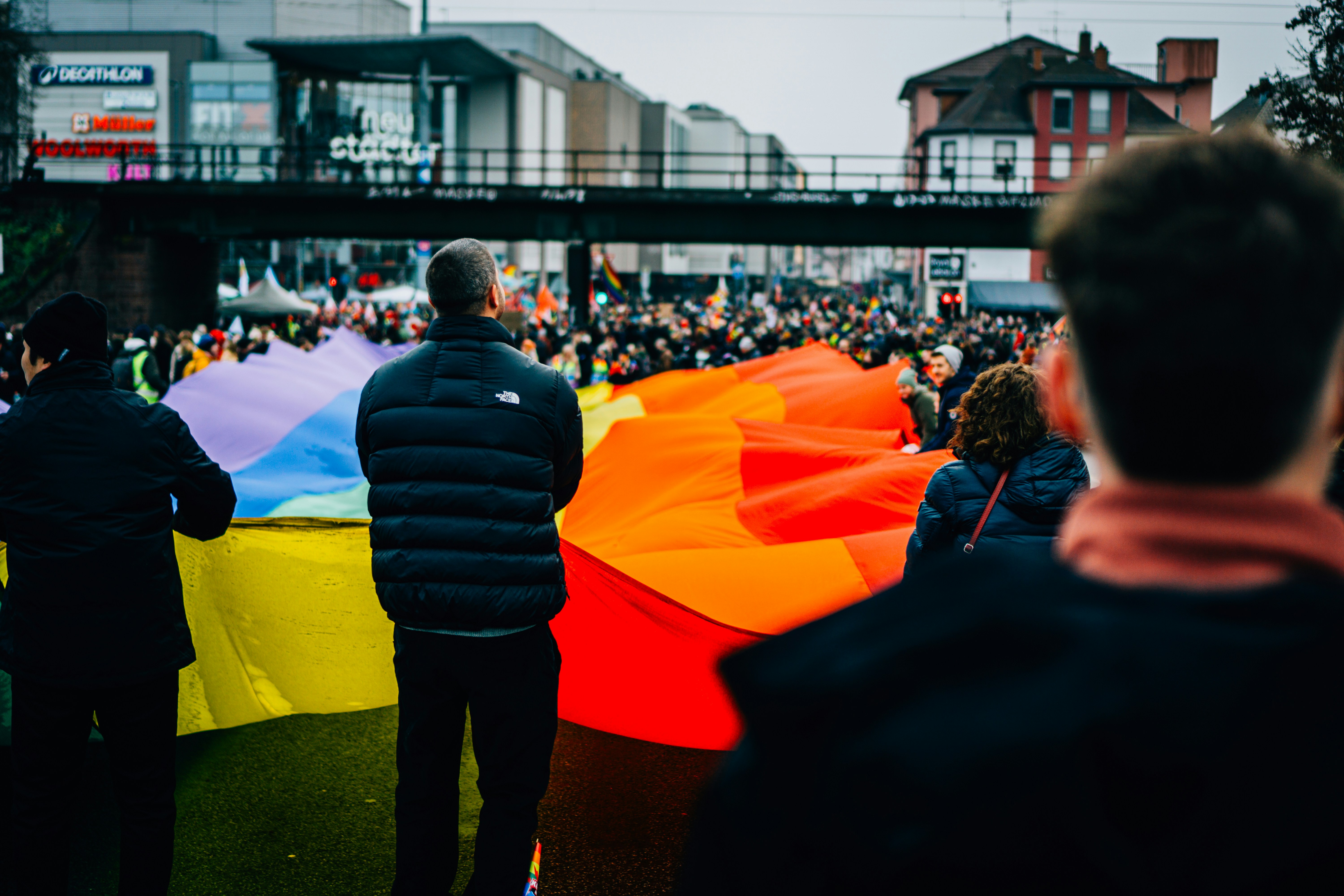 People holding a large rainbow flag during a parade.