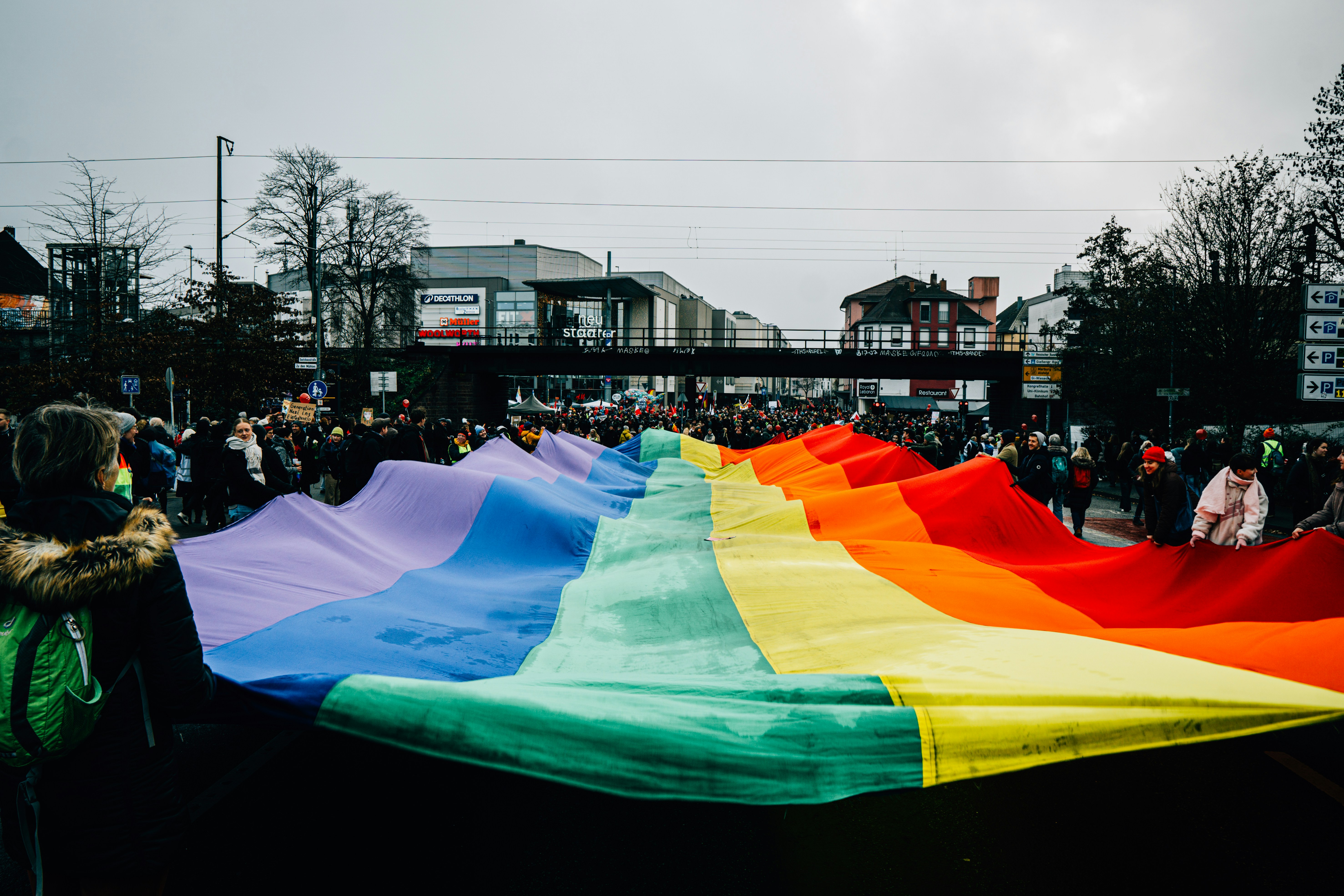 People hold a large rainbow flag during a parade.