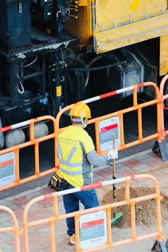 Worker in safety vest and hard hat near construction