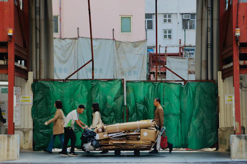 Movers wheeling large items on a moving cart