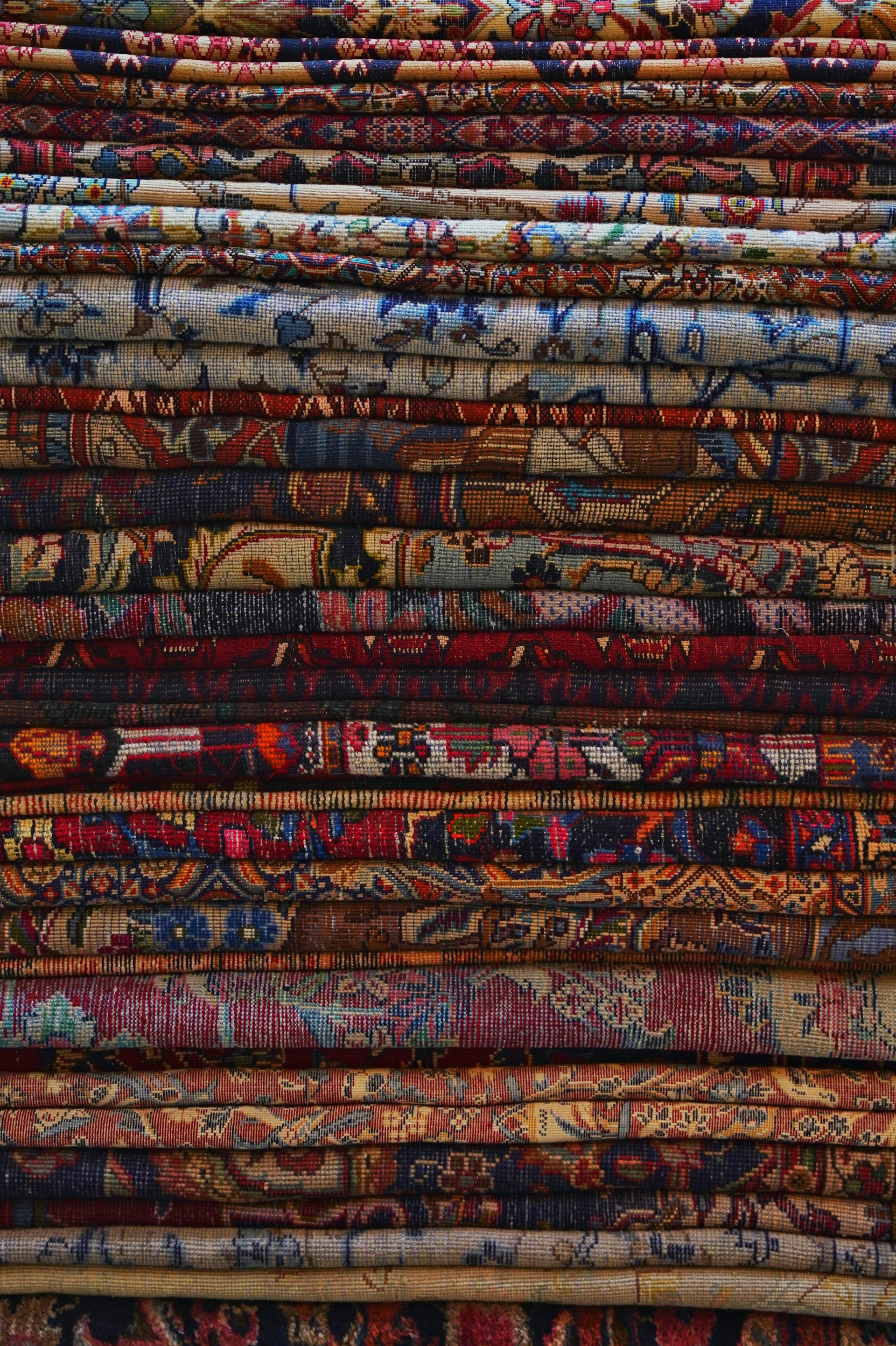 Stack of colorful patterned carpets with intricate designs