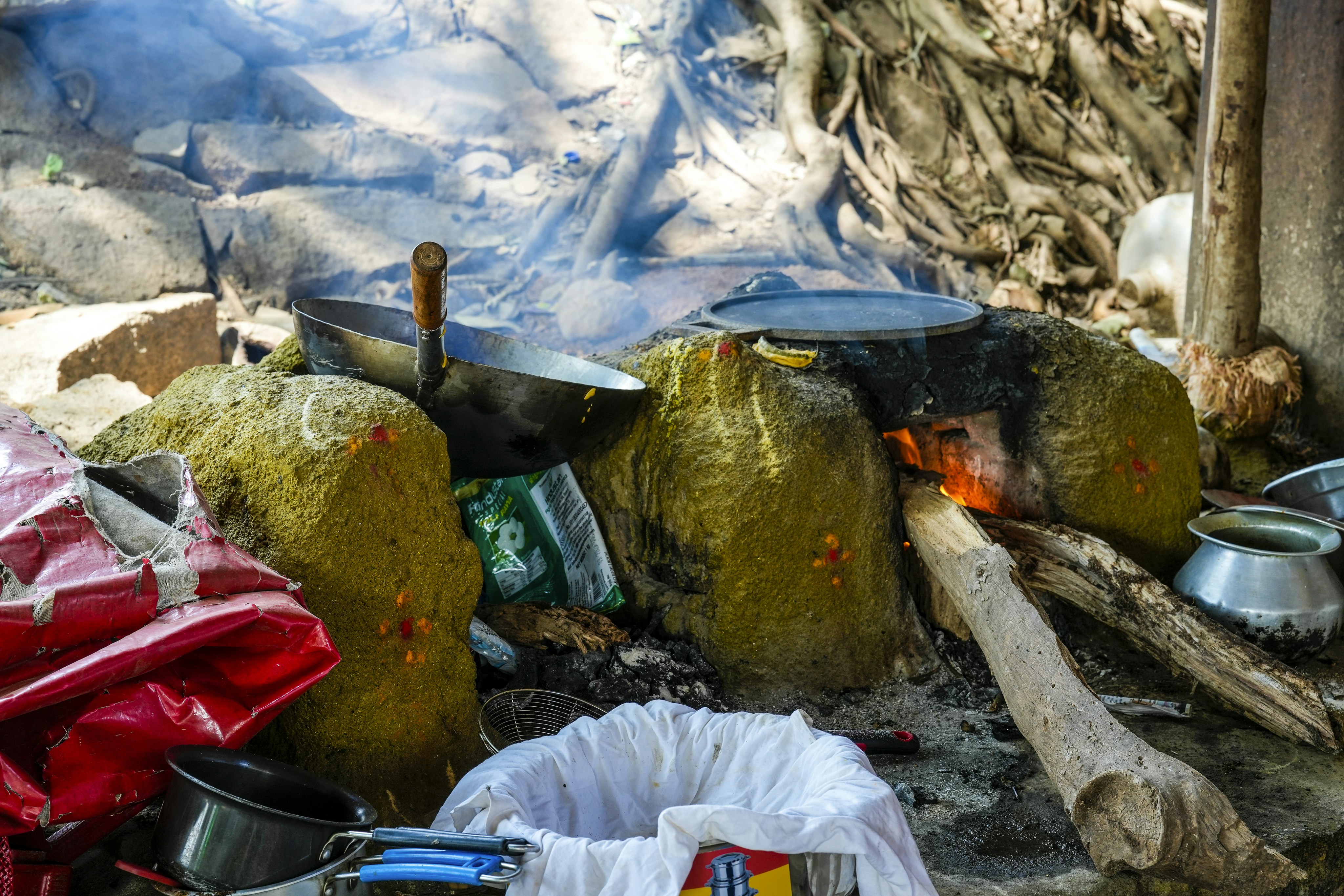 Cooking over an open fire with pots and pans.
