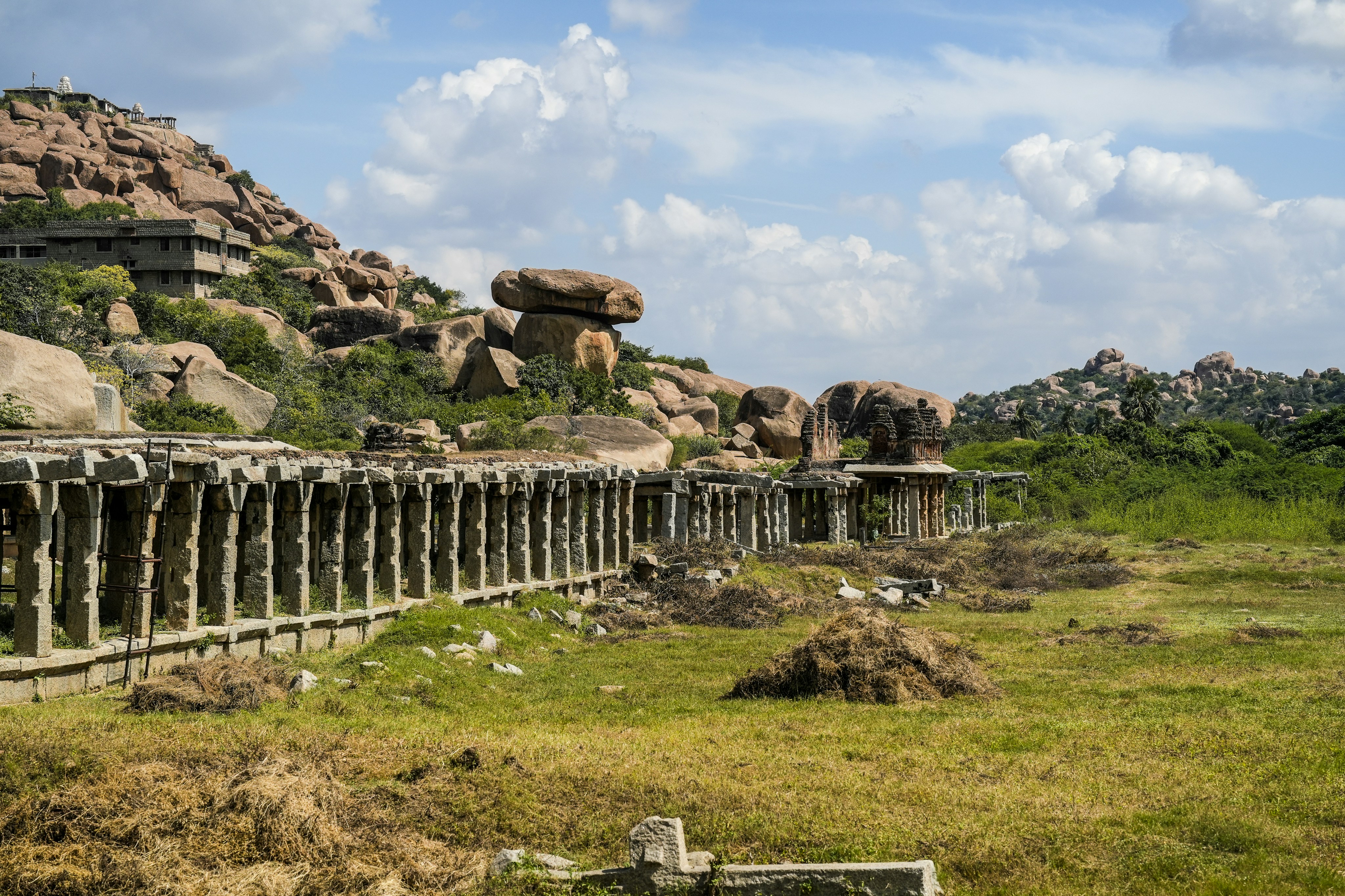 Antica colonnata in pietra con colline rocciose e fogliame verde
